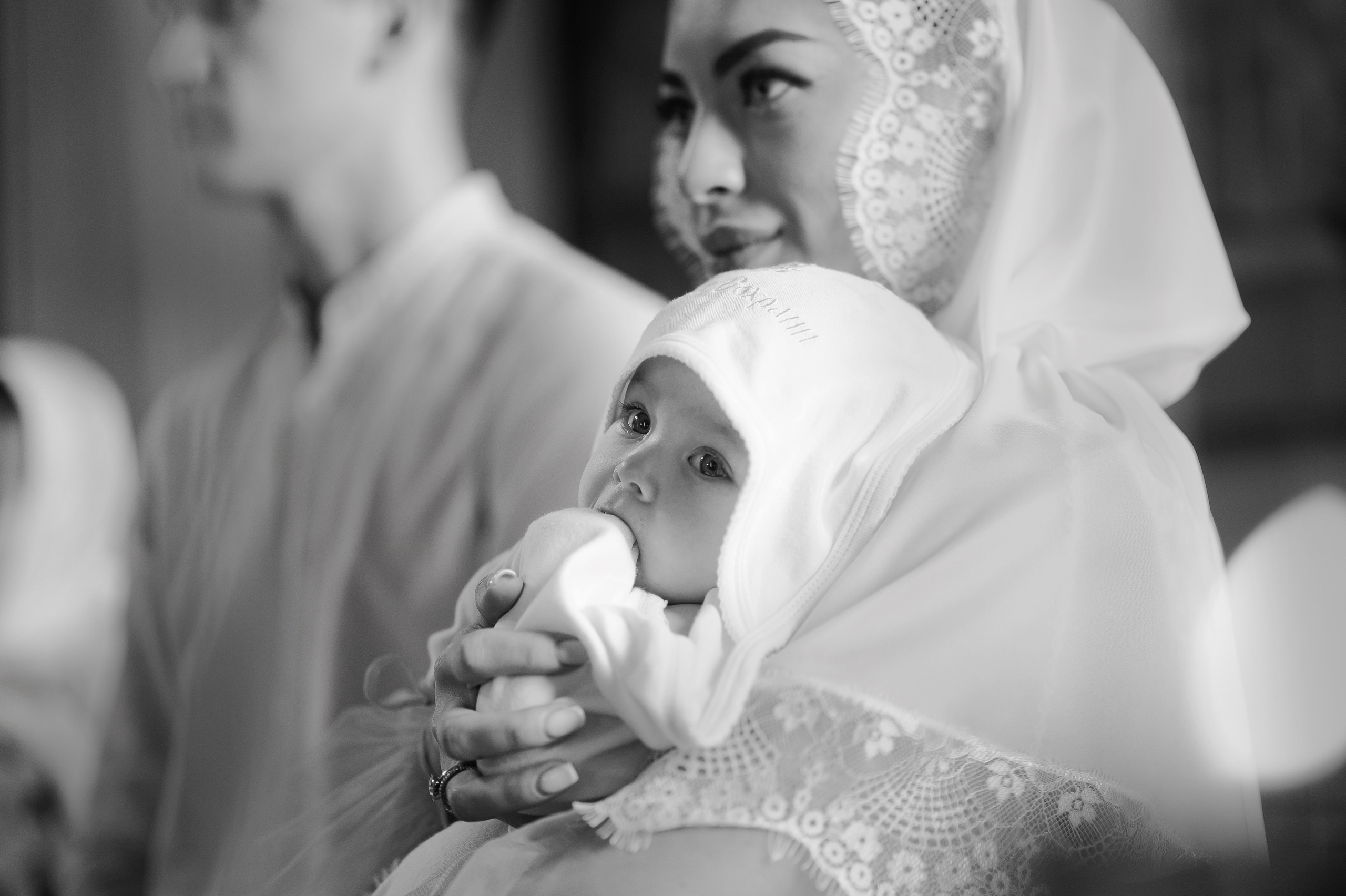 Во время крещения крестная держит ребенка на руках, а он засунул палец в рот