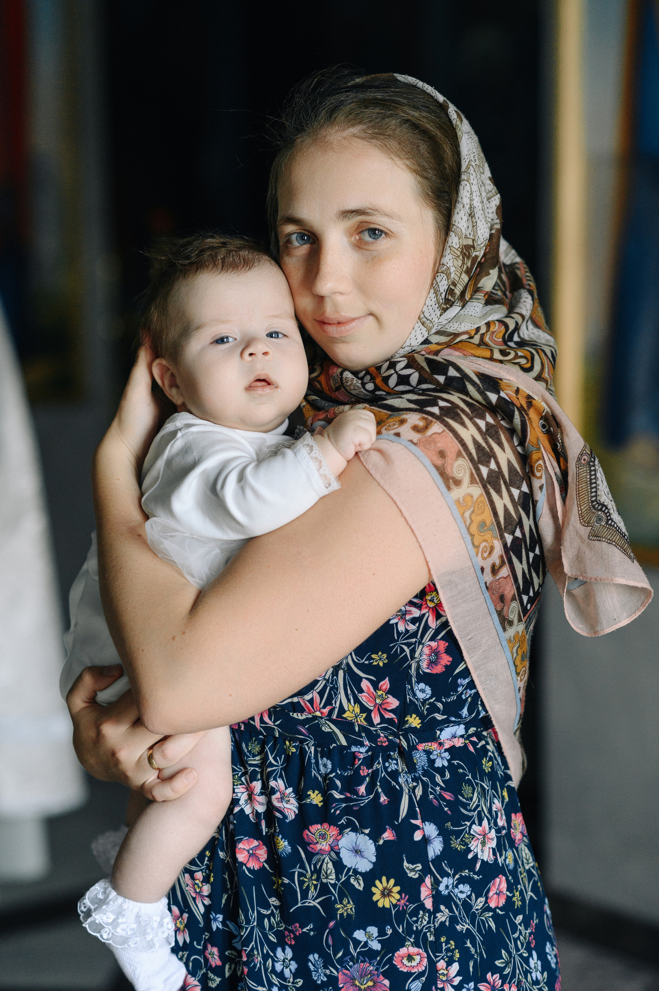 Младенца держат на руках а он смотрит на фотографа