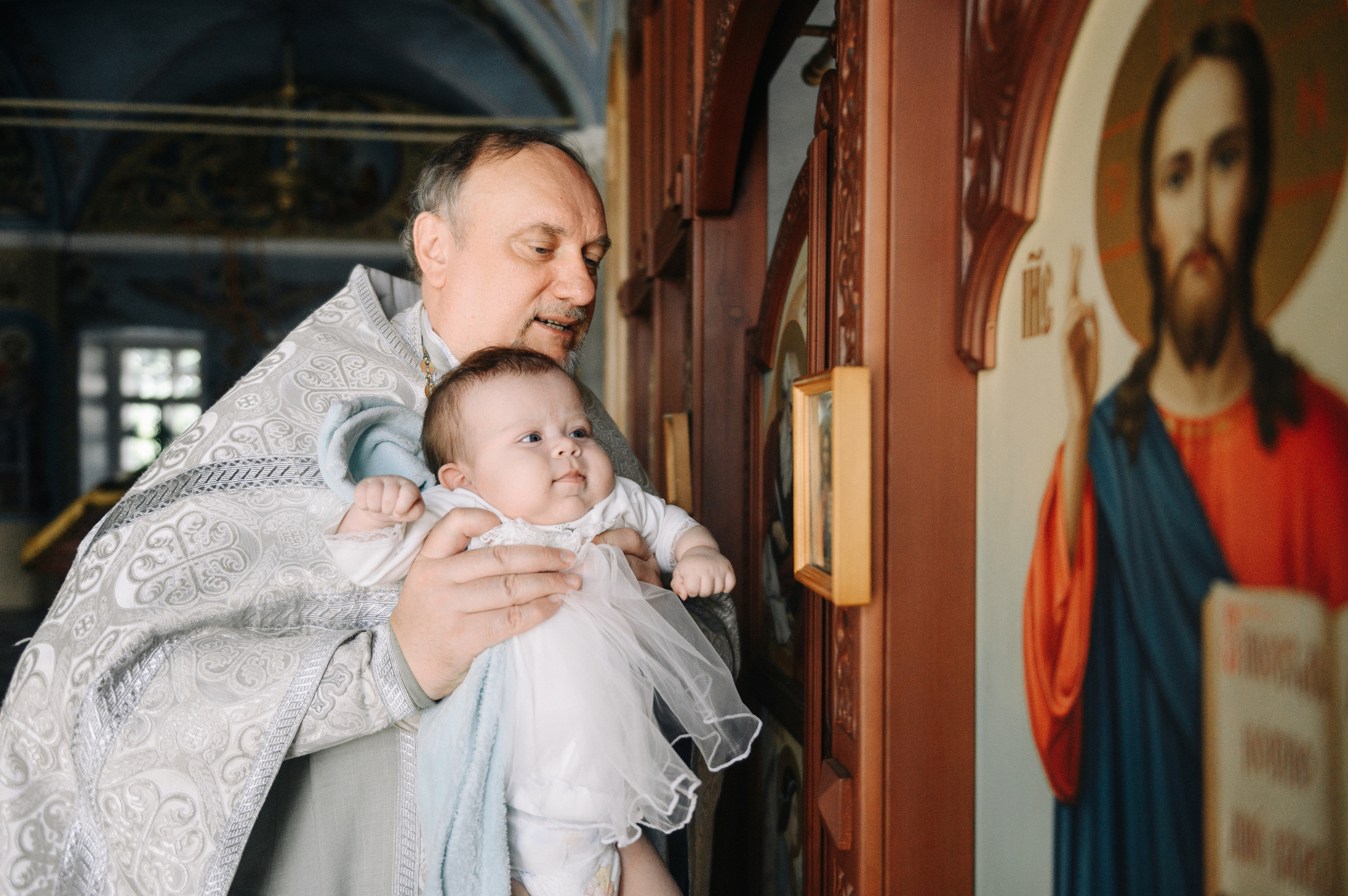 Батюшка взял ребенка и поднес его к иконам