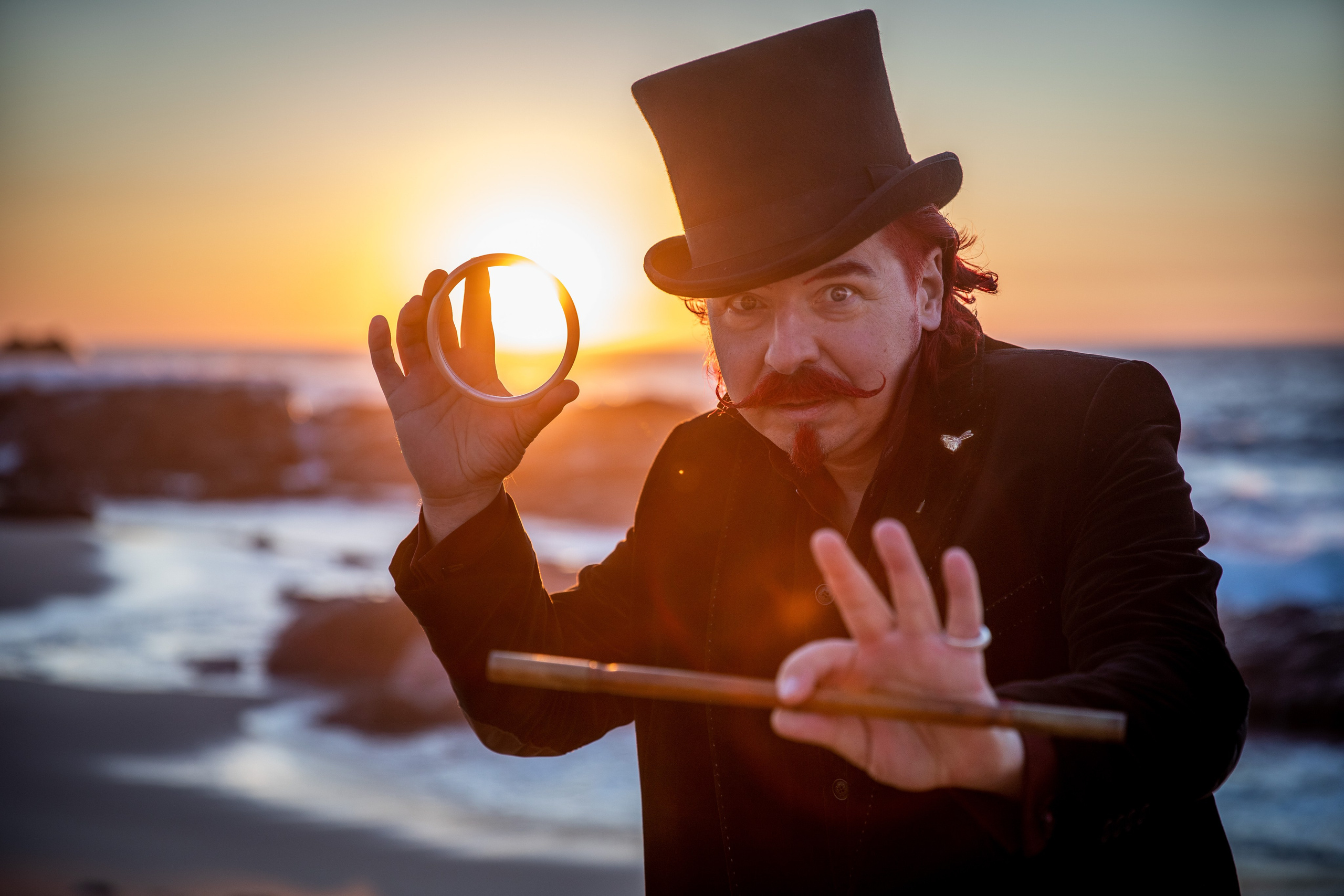 Illusionist and magician walks on the beach and shows tricks. Photo shoot for a magician with a red moustache