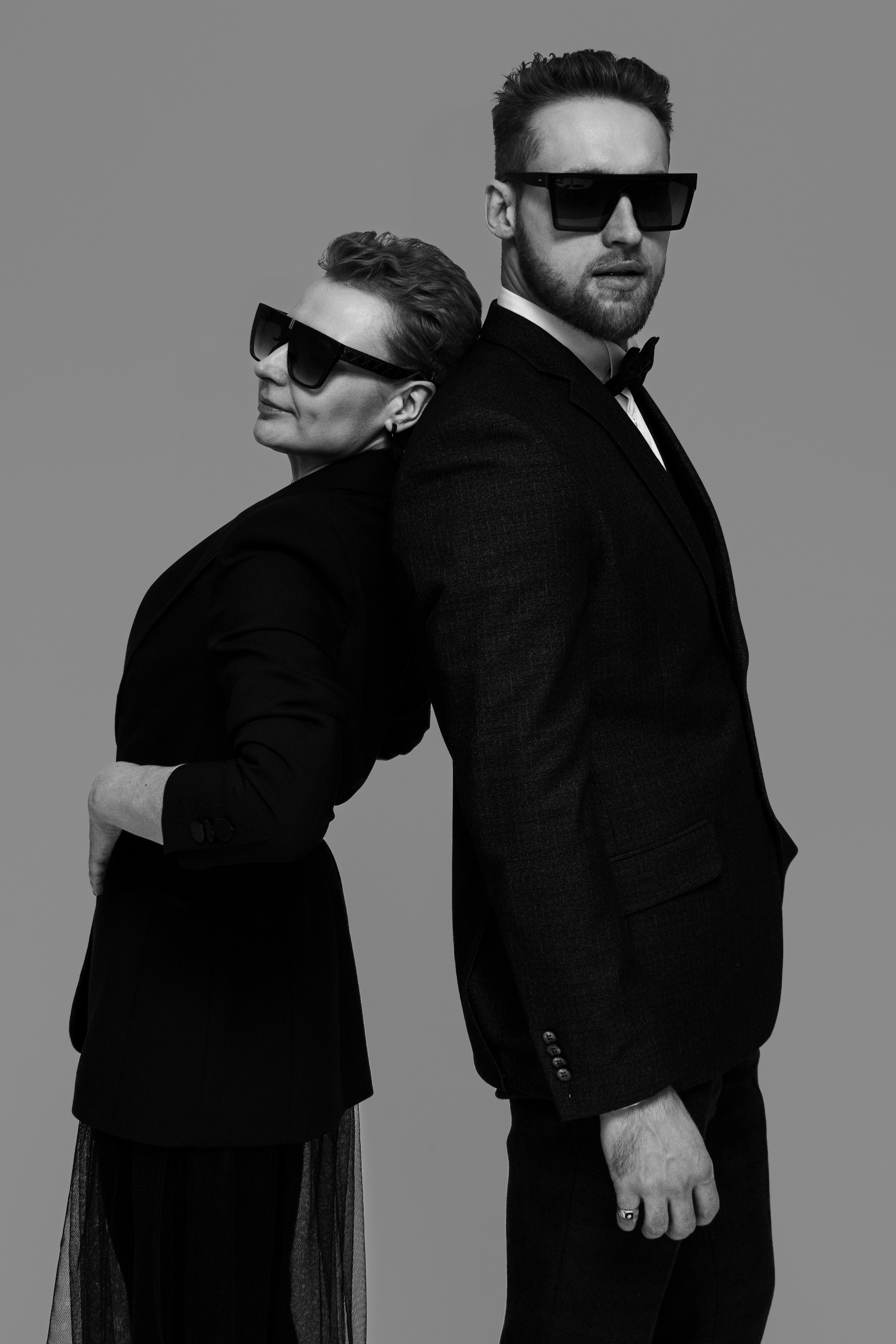 Черно-белая фотография с женщиной и мужчиной, позирующие в пиджаках и темных очках