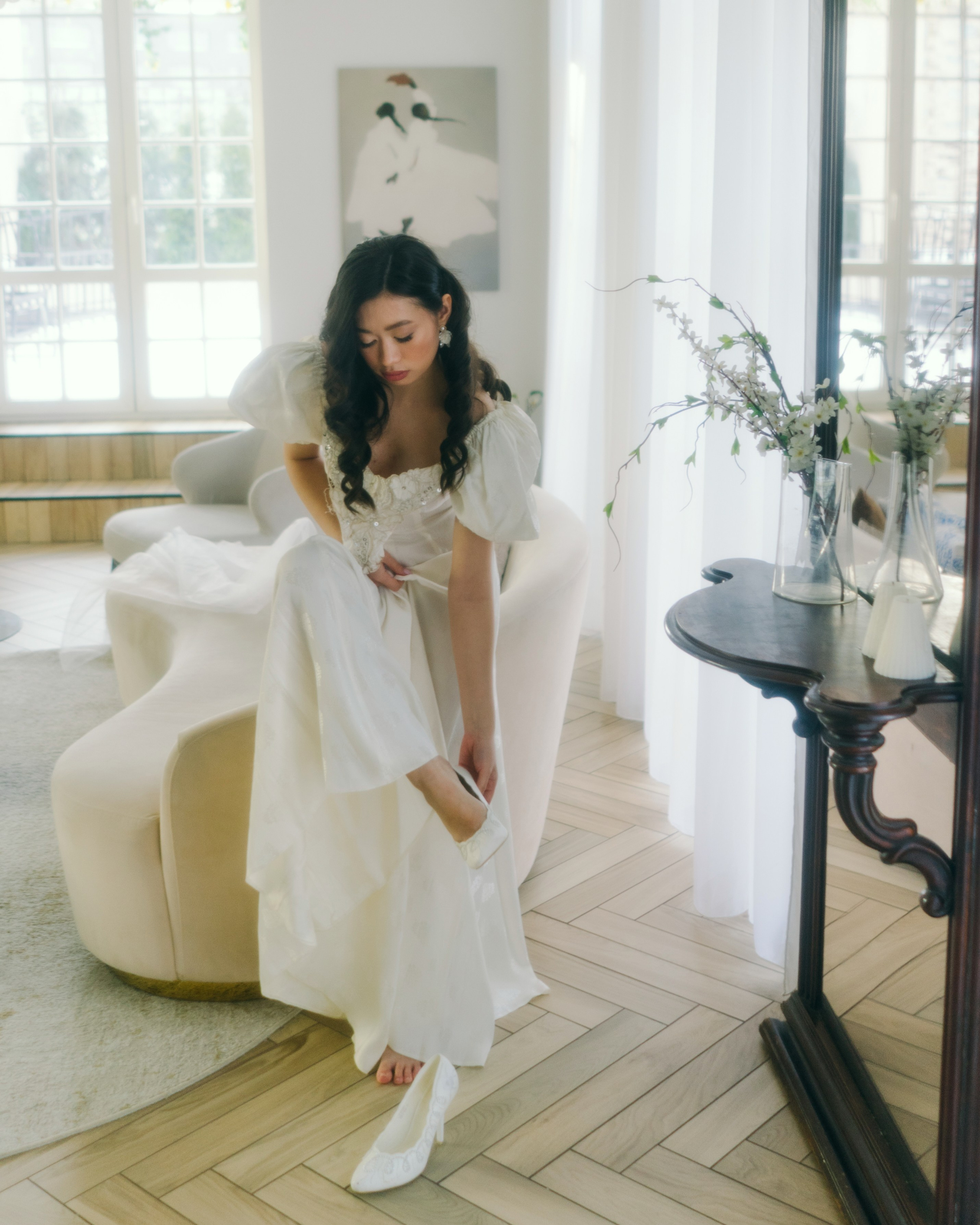 Утро невесты в фотостудии, невеста в белом платье сидит у окна, светлая авторская свадебная фотосессия