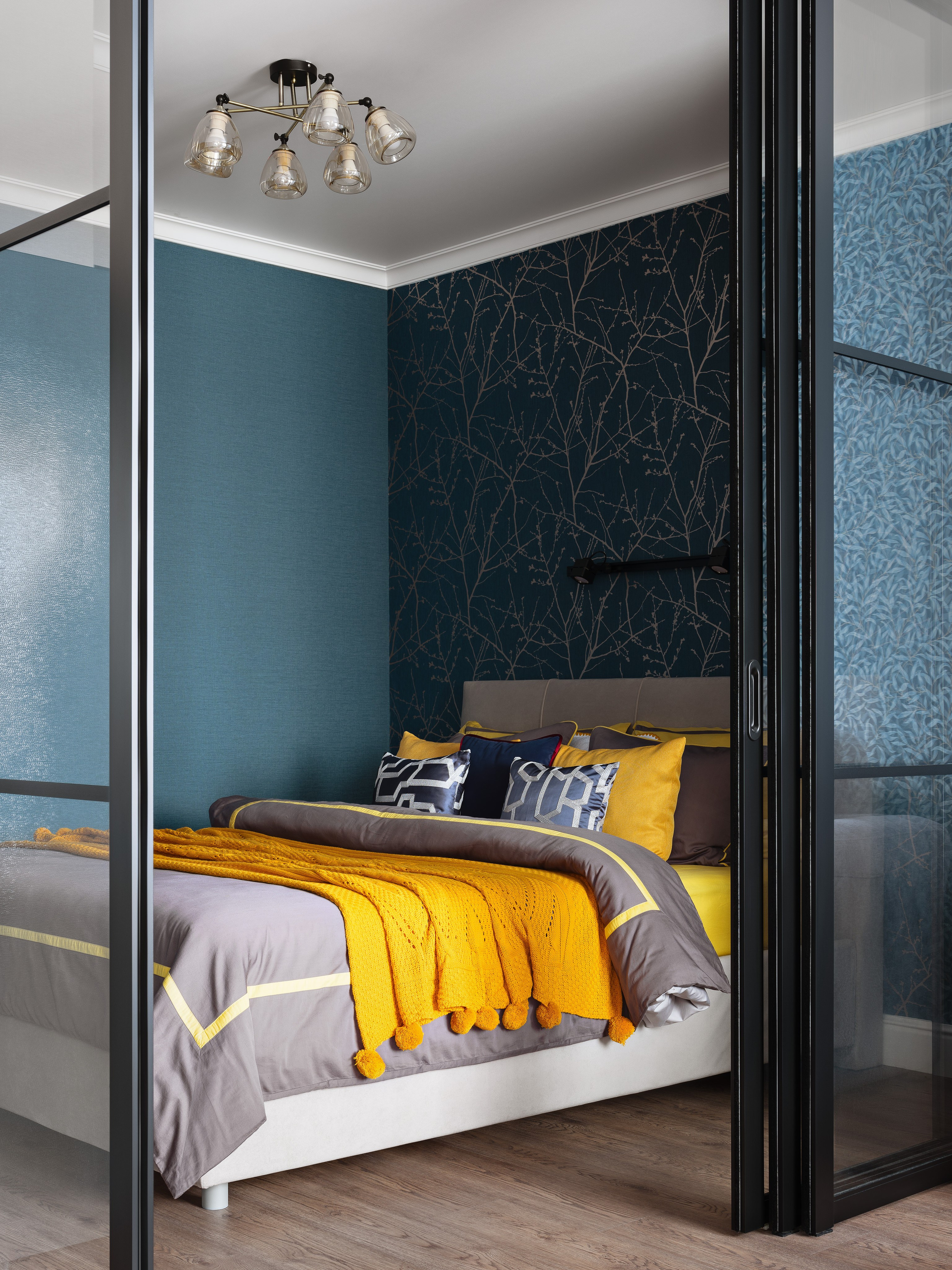 Современный дизайн интерьера спальни в стильных синих тонах с ярким желтым пледом и декоративными подушками. Фото создает атмосферу уюта и гармонии. Дизайнер Лилия Горожеева, фотограф Сергей Денисенко.