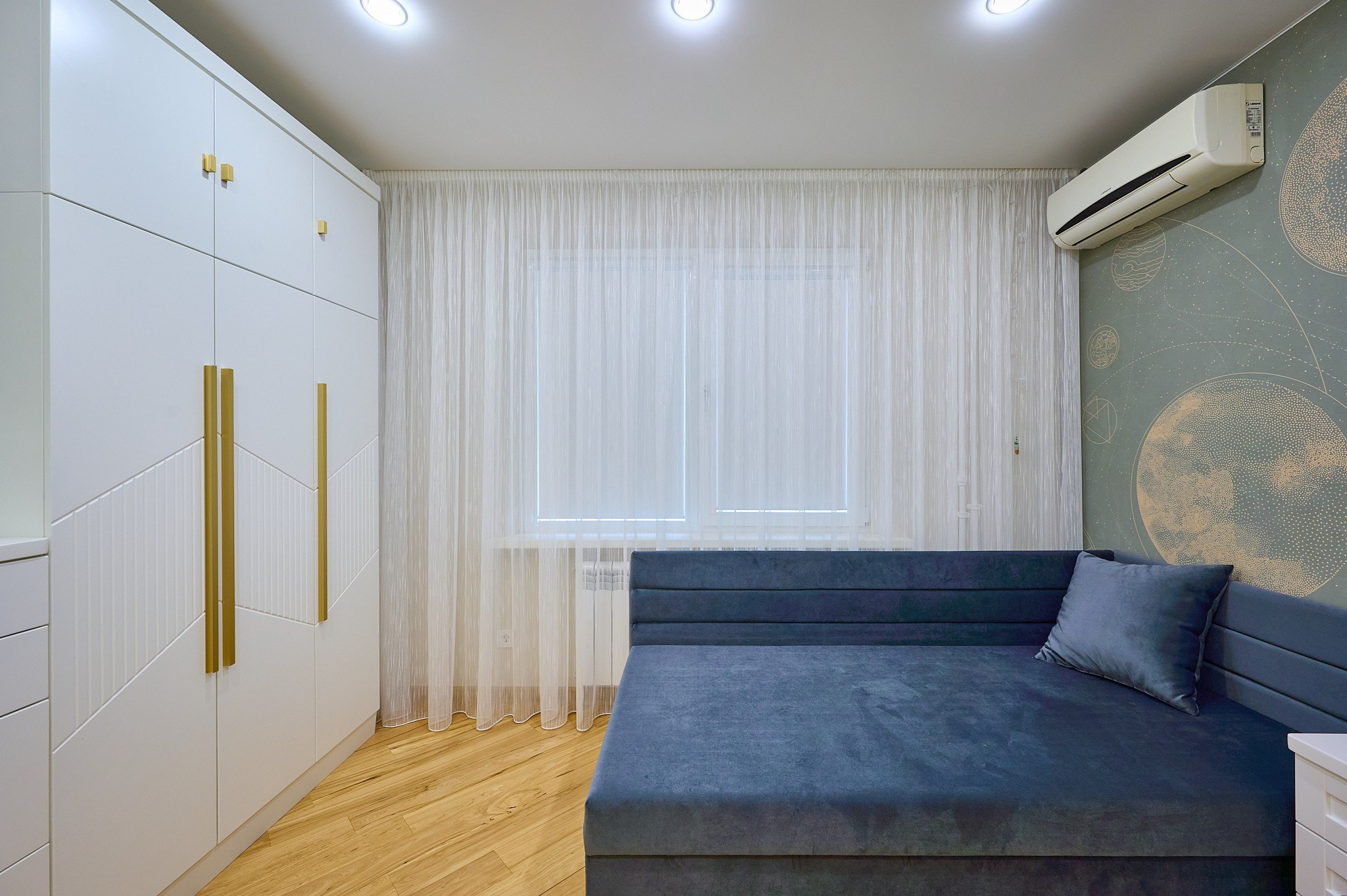 комната цветная стена синий диван большой белый шкаф белая тумба у кровати 