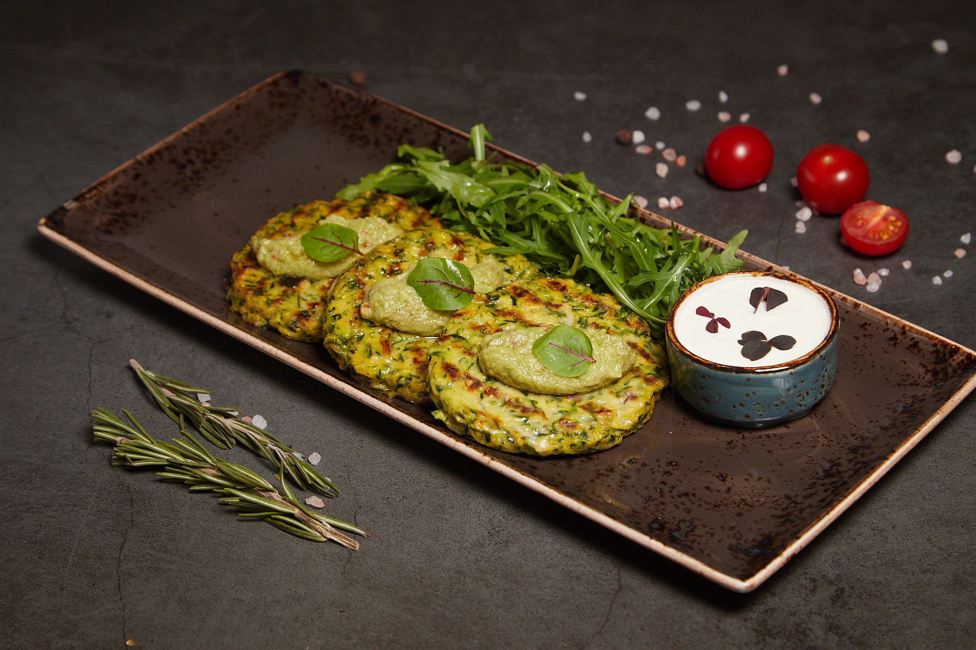 Фуд-фотография драников с соусами на голубой тарелке.