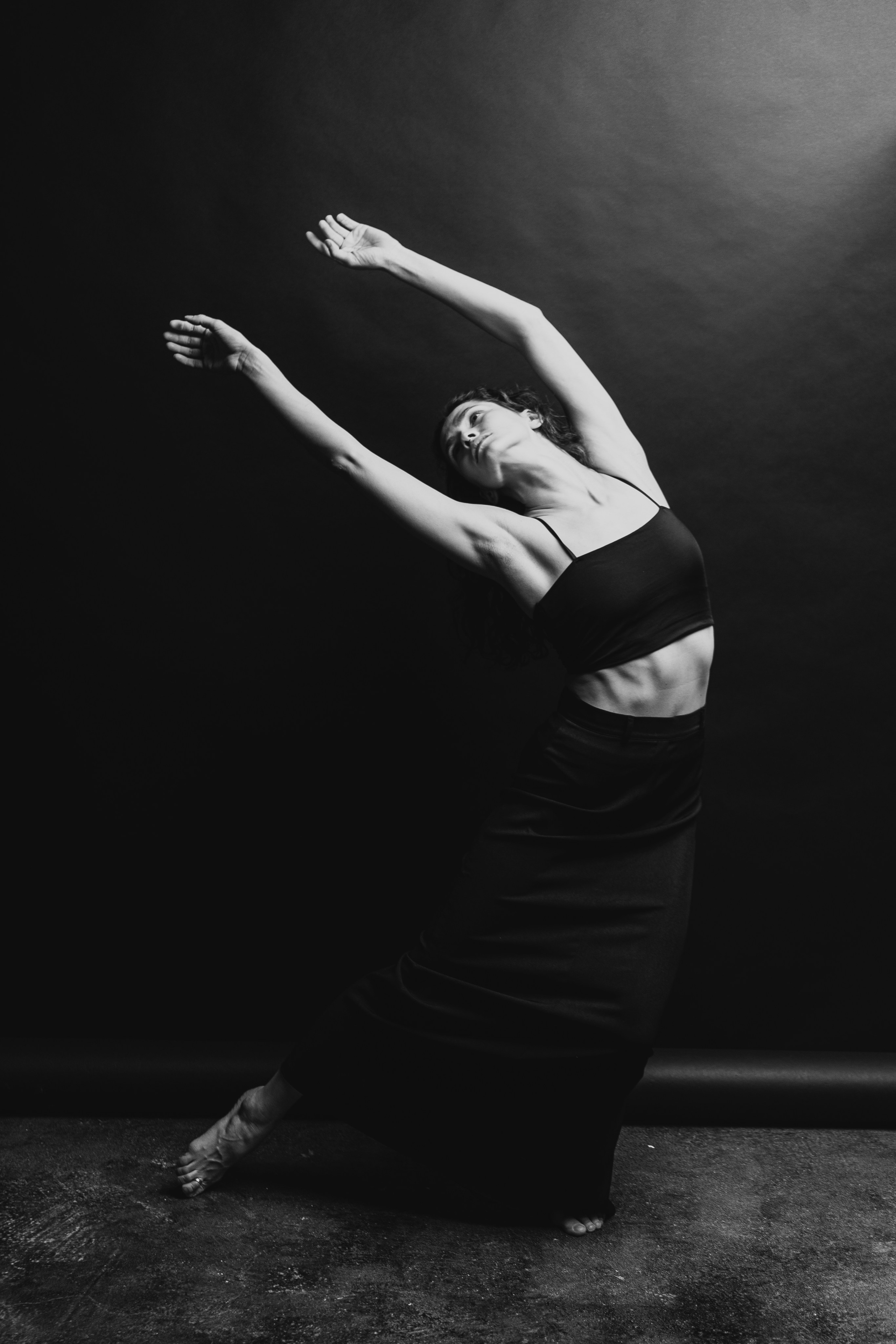 Хореограф танцует на тёмном фоне в тёмной одежде