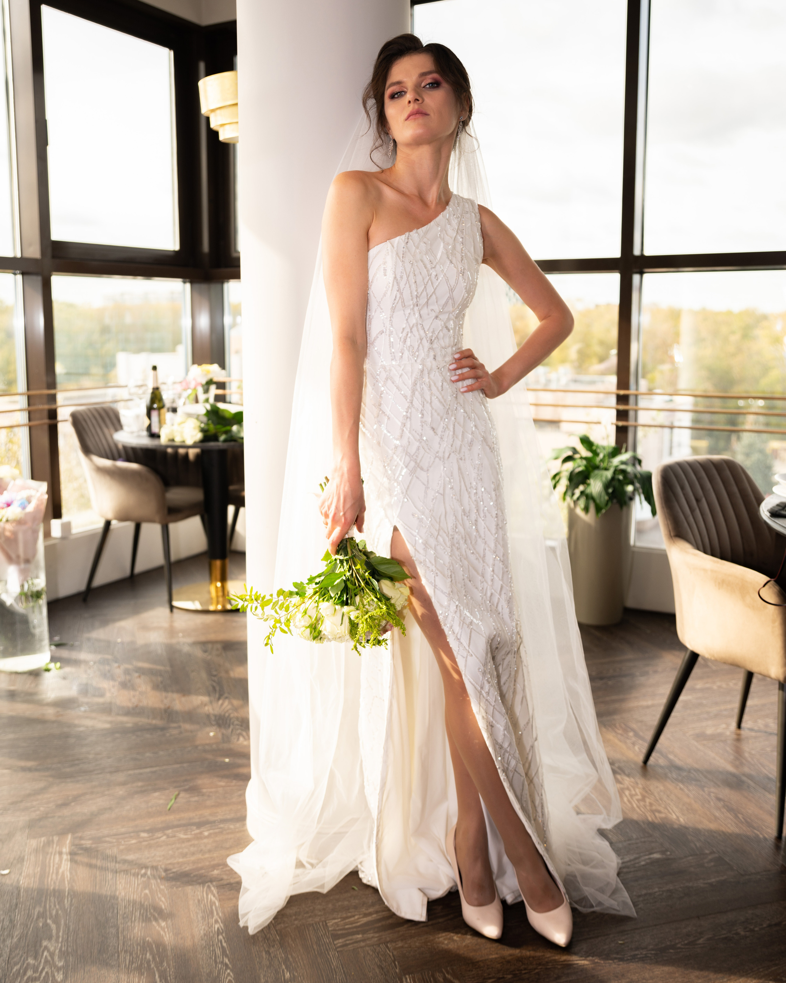 Невеста с цветами в ресторане у столба. Белое платье