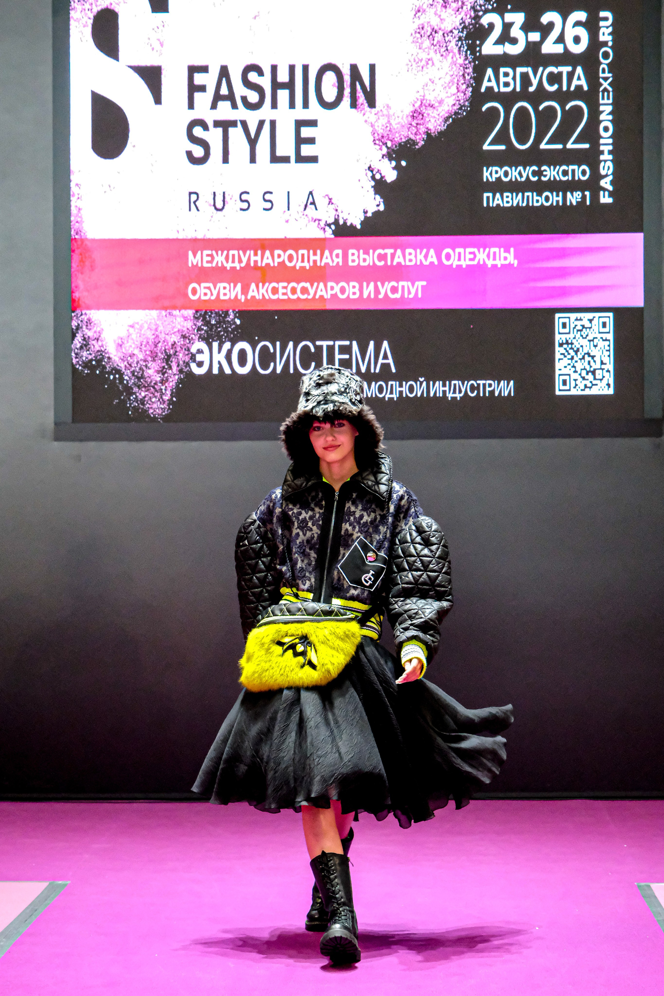  "Модели в ярких нарядах проходят по подиуму во время показа мод, освещенные яркими софитами и окруженные восторженными зрителями."