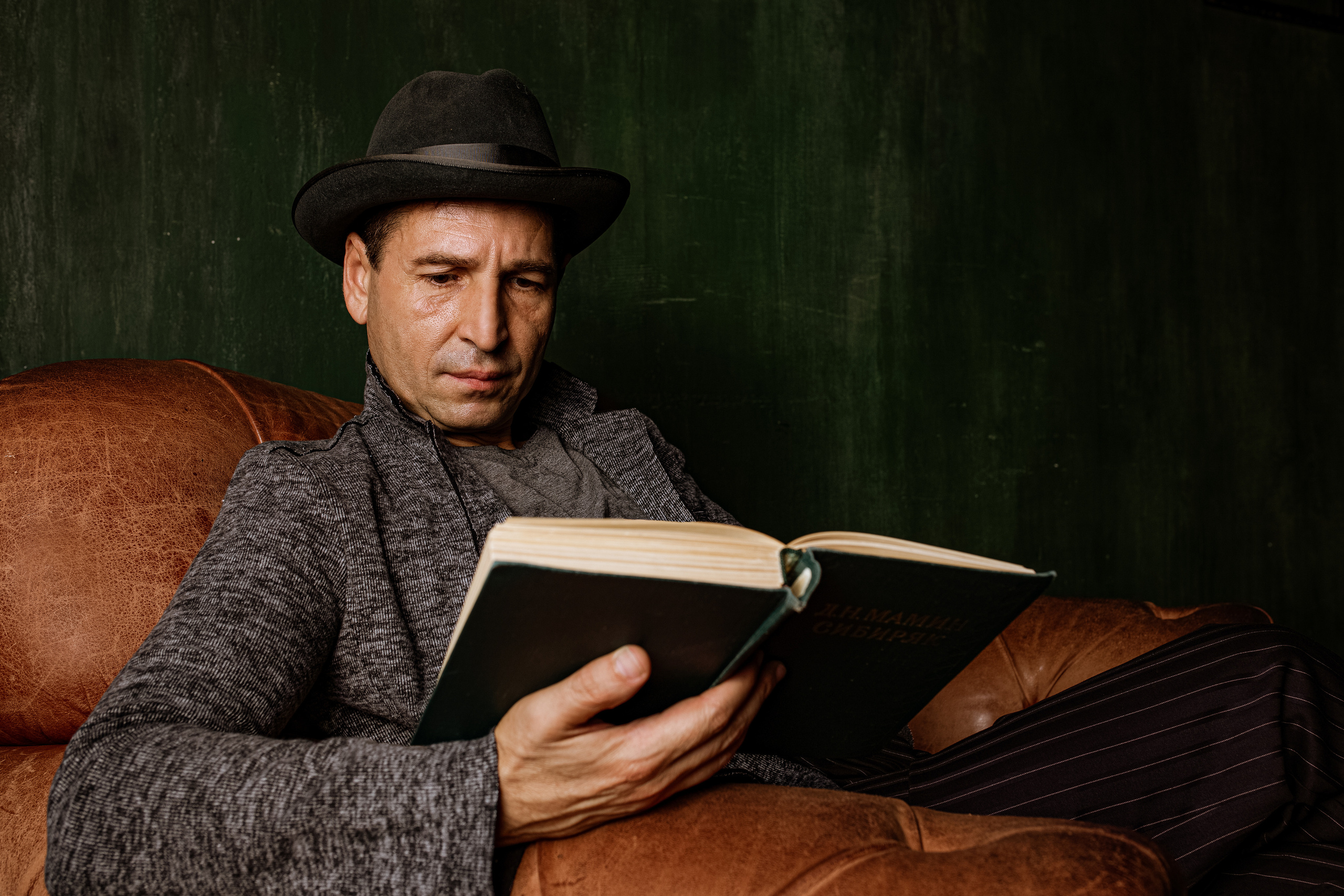 Актёр Олег Карин сидит в кресле и читает книгу