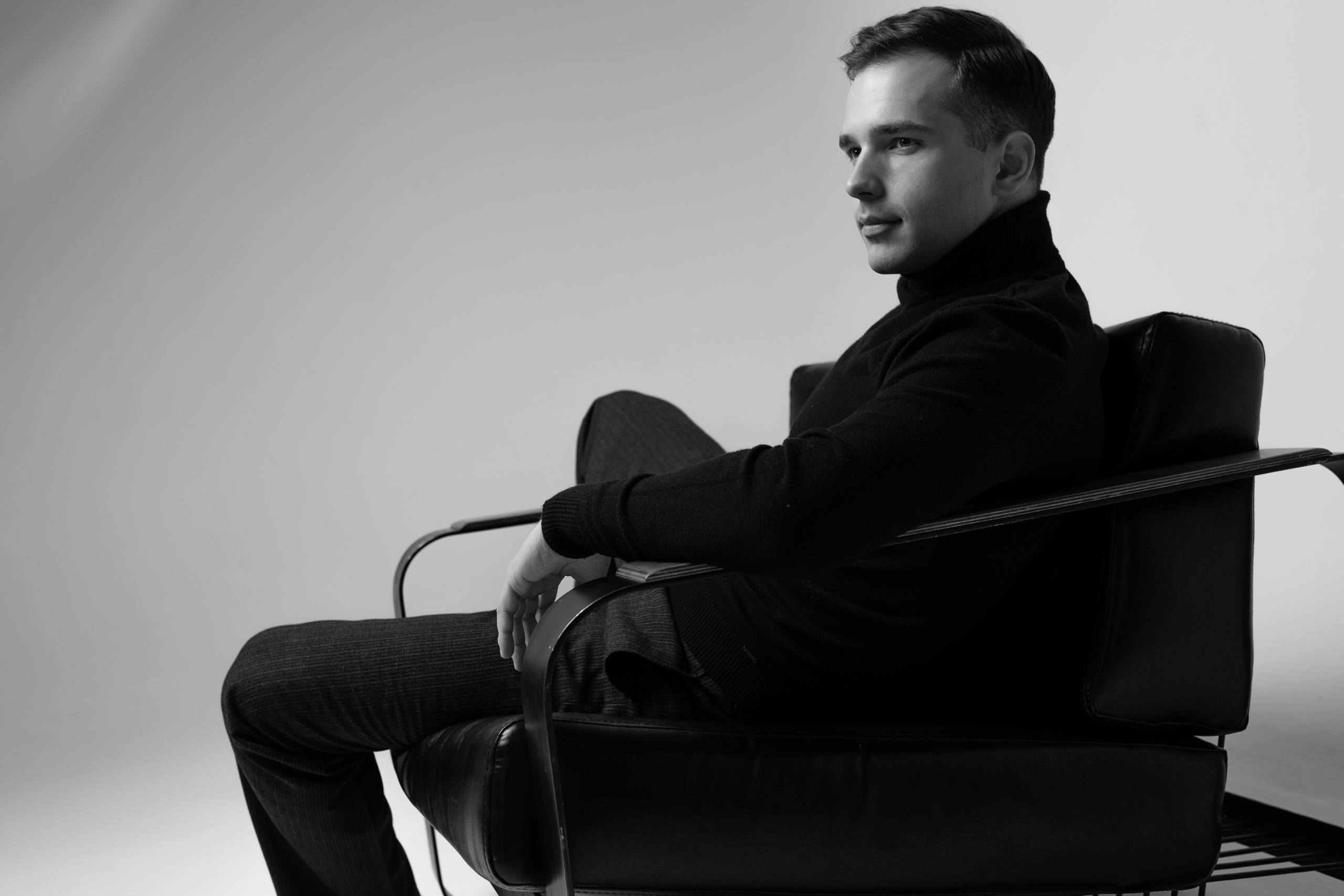 чёрно-белая фотография в студии на которой парень сидит в стильном кресле