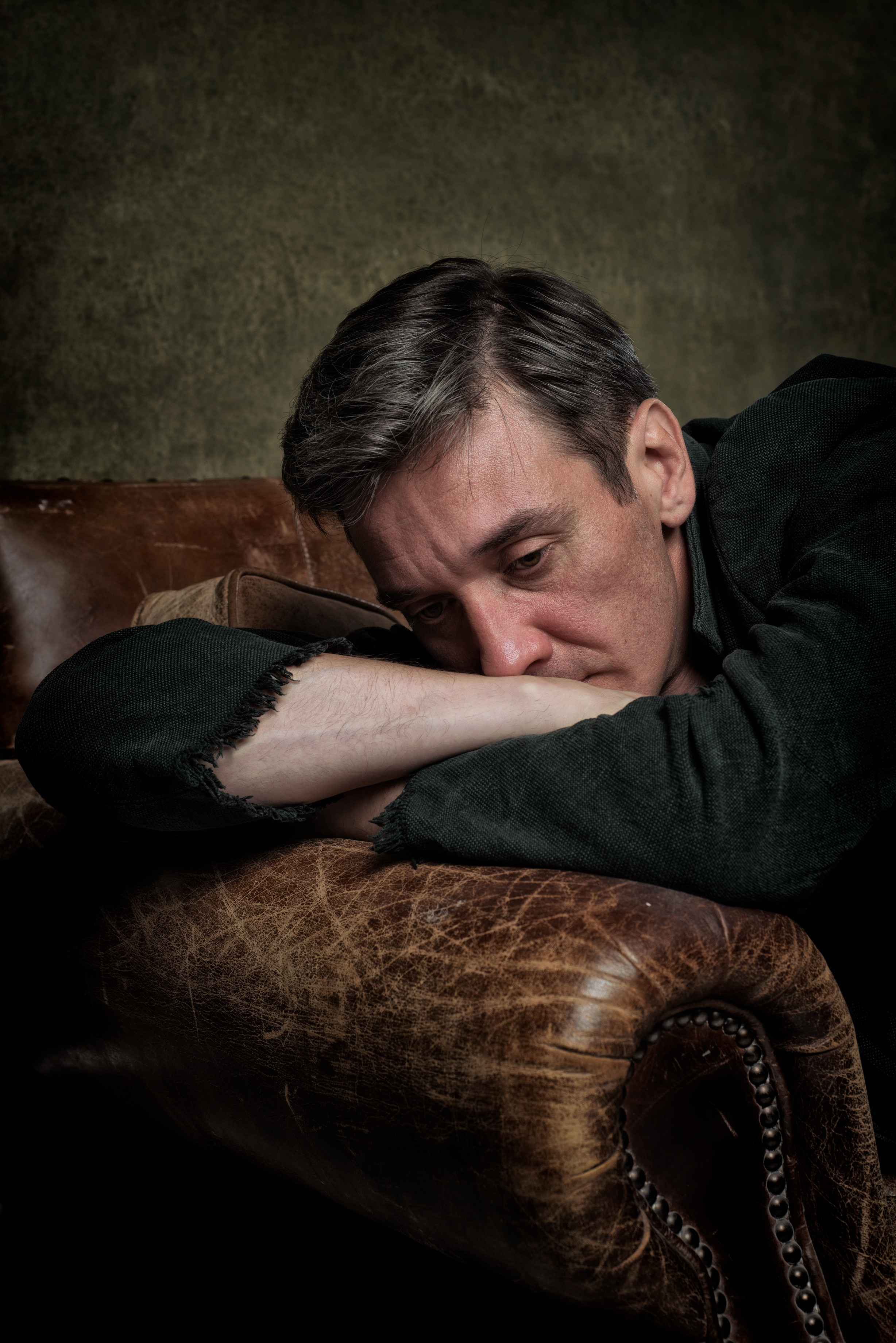 классический мужской портрет в коричневых тонах, мужчина в пальто на кожаном диване 