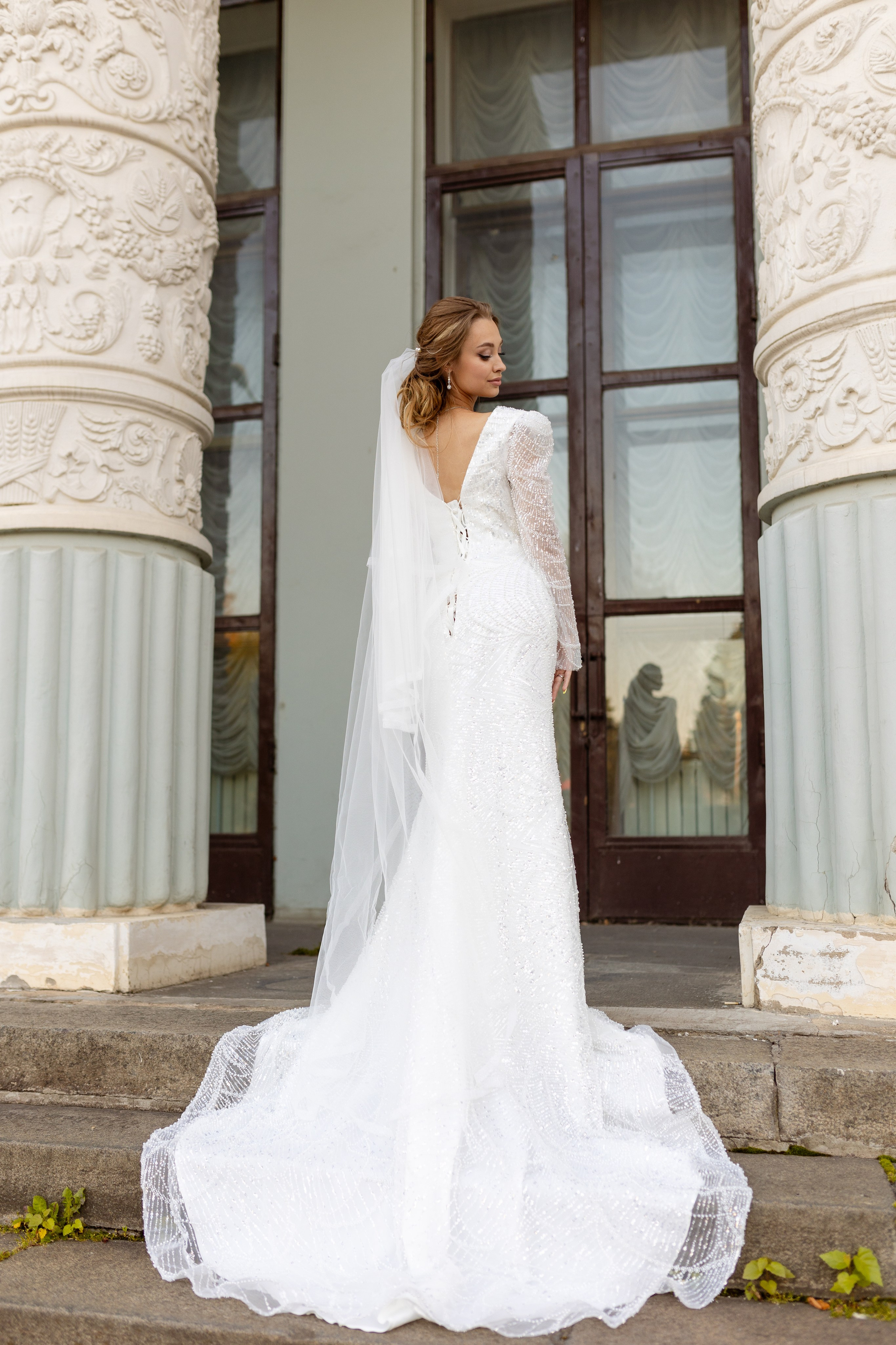 Невеста в прекрасном платье со шлейфом во весь рост одна.