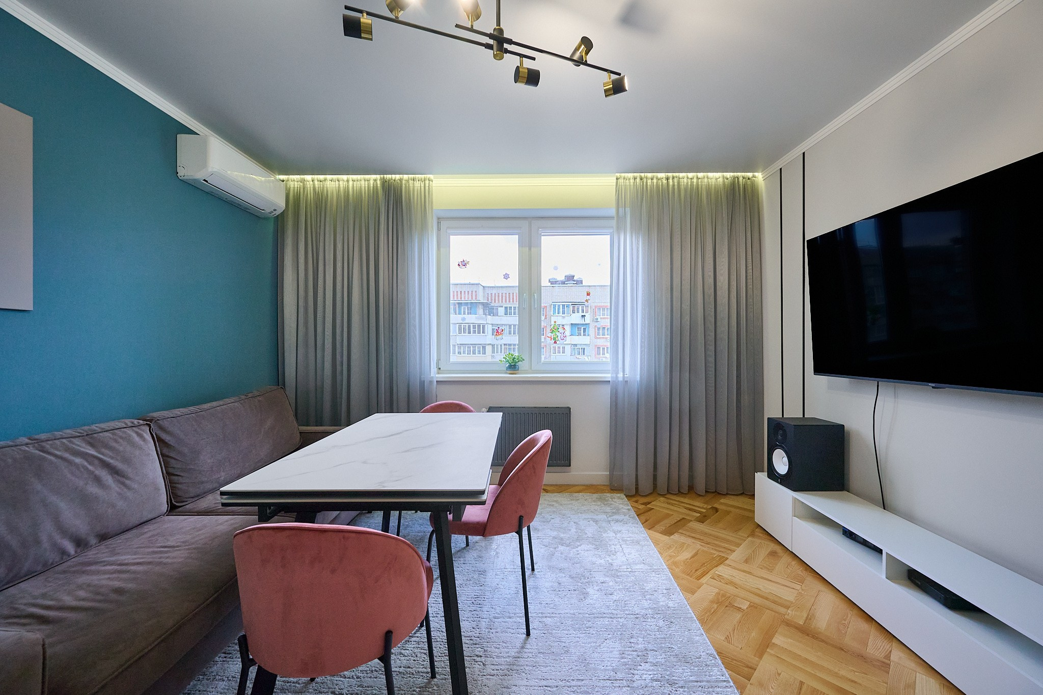 гостиная серый диван белый стол розовые стулья светлые шторы телевизор 