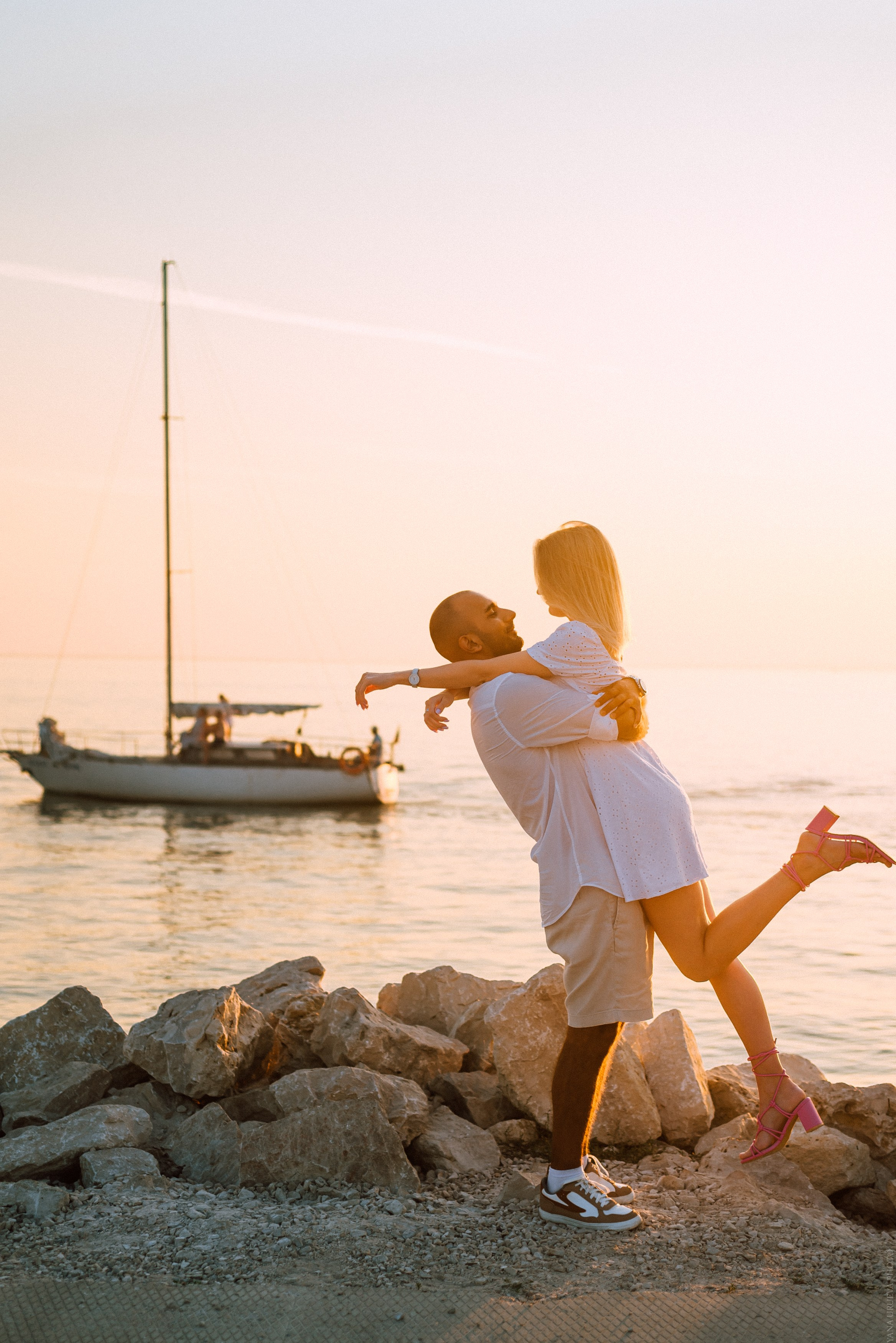 паре поднял девушку на закате на фоне яхты