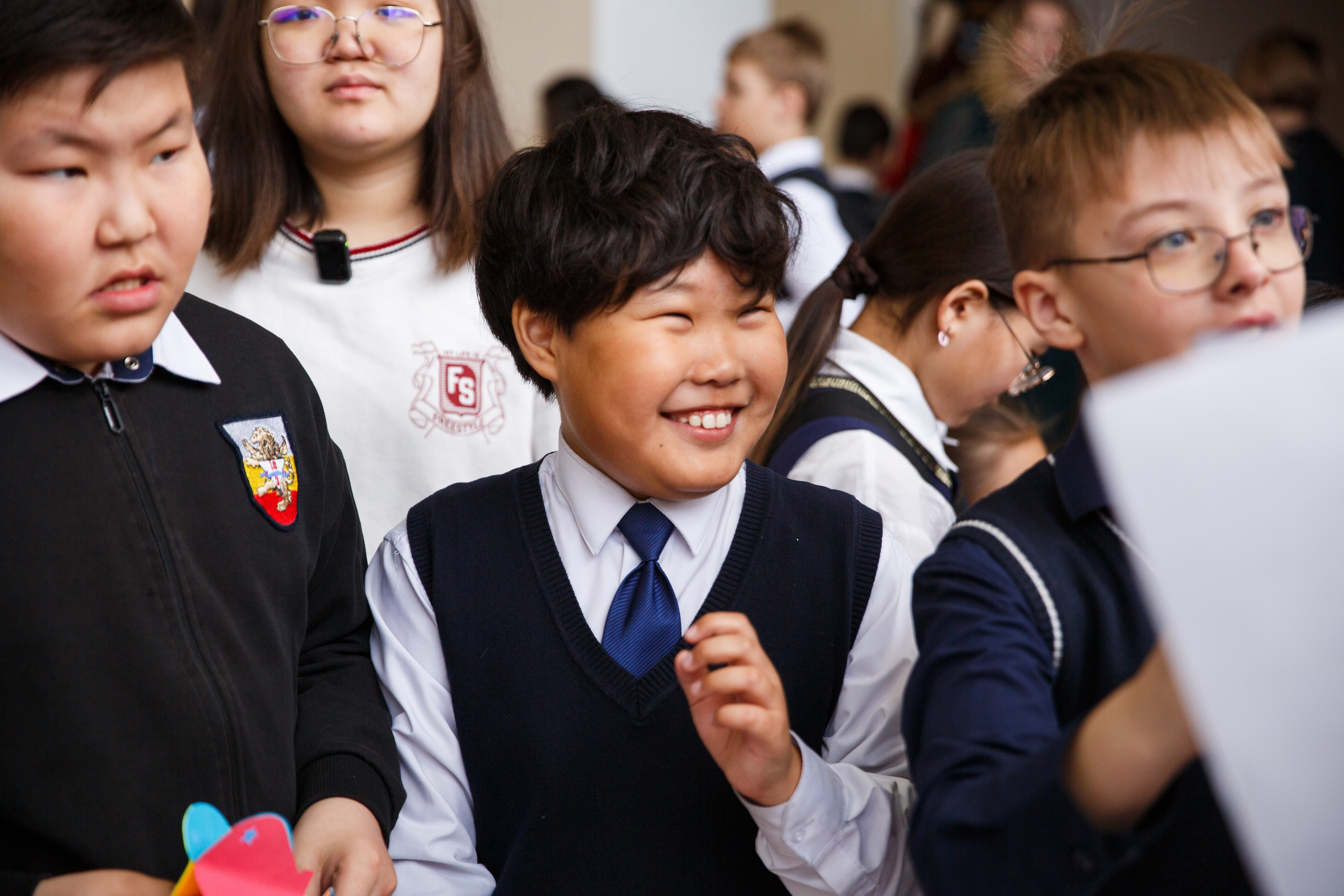 Группа детей с поднятыми руками, все в школьной форме.