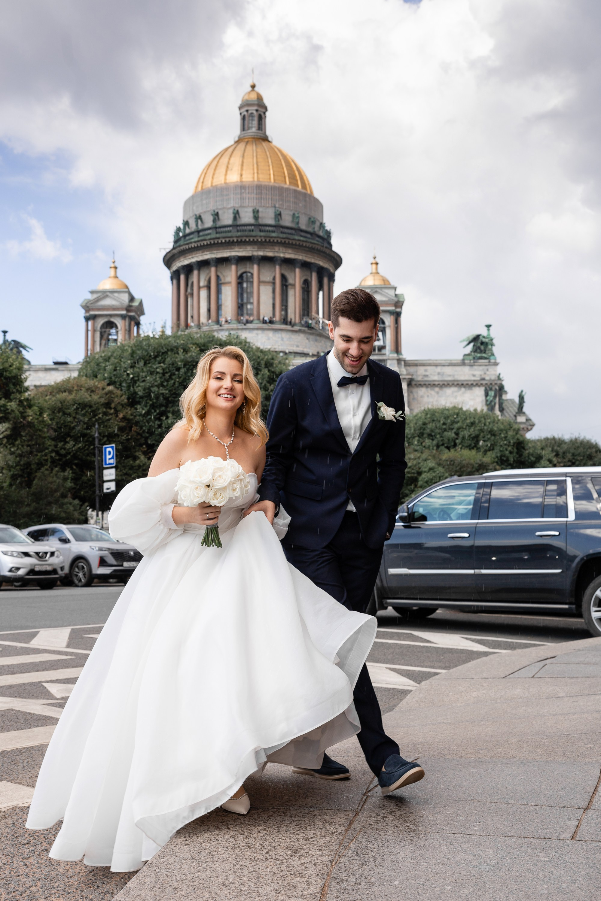 Жених и невеста переходят дорогу на фоне Исаакиевского собора