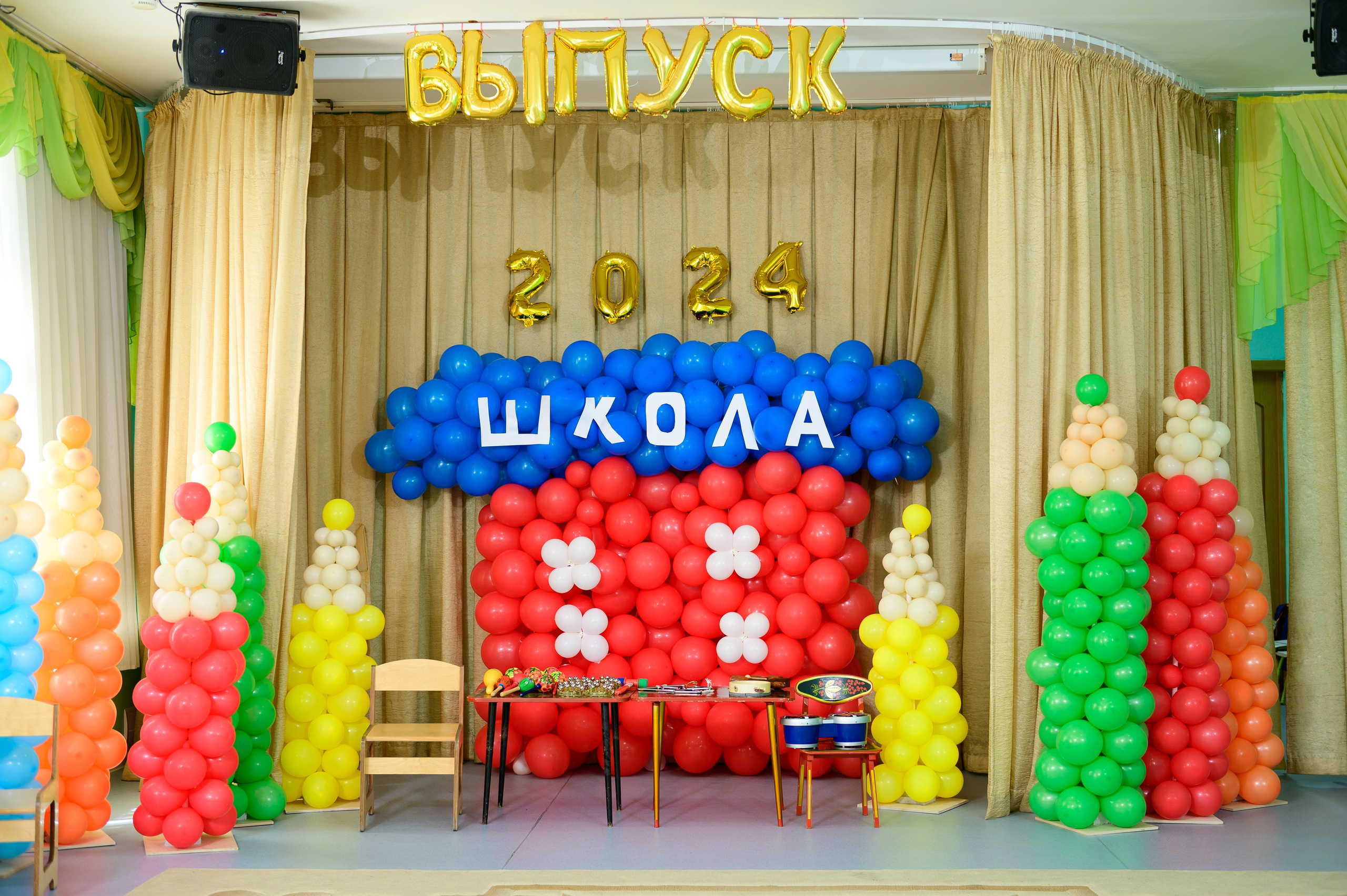 Актовый зал в детском саду, украшенный воздушными шарами перед утренником.