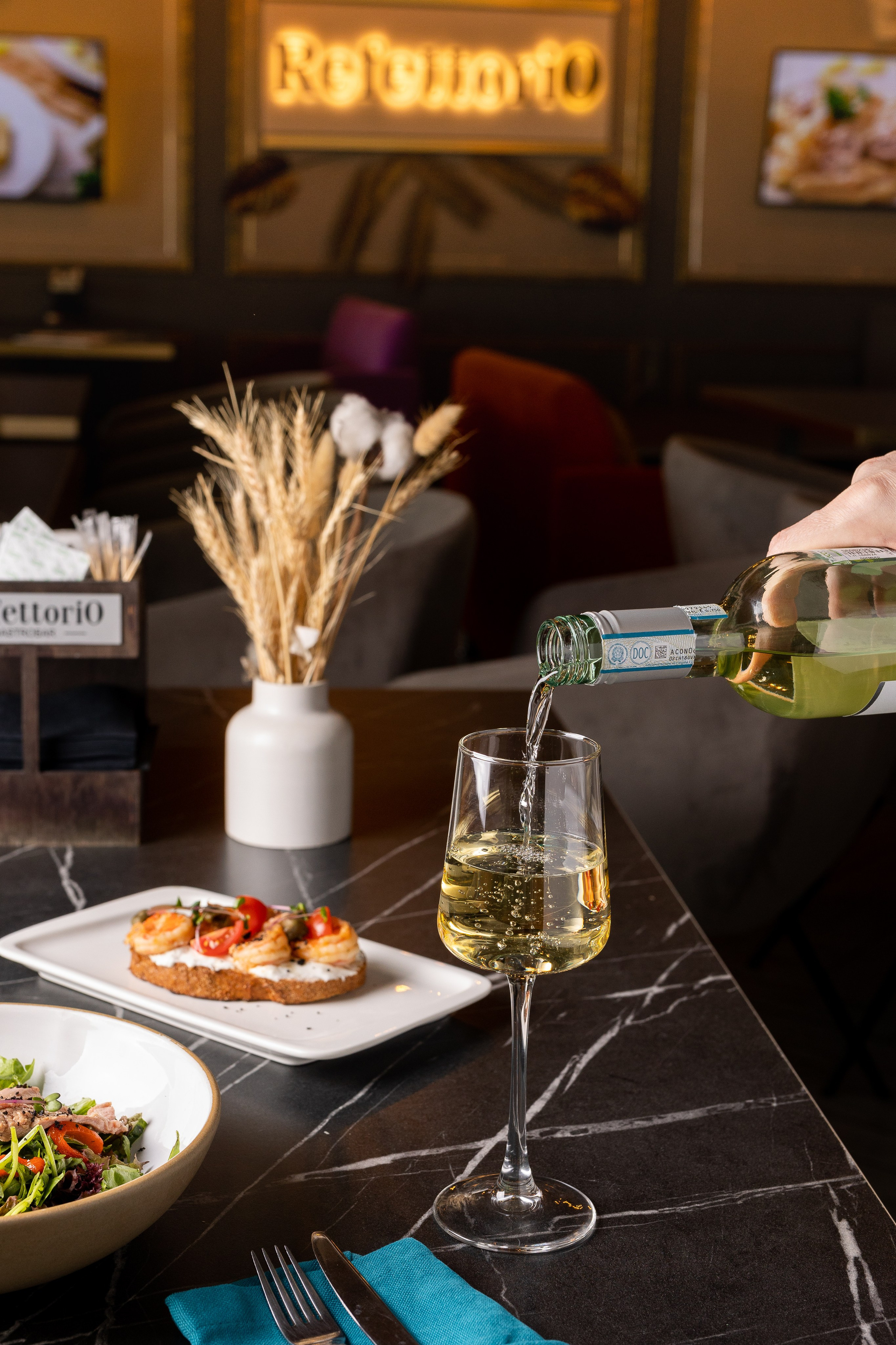 Интерьерная съемка кафе и ресторана. Официант наливает вино в бокал.