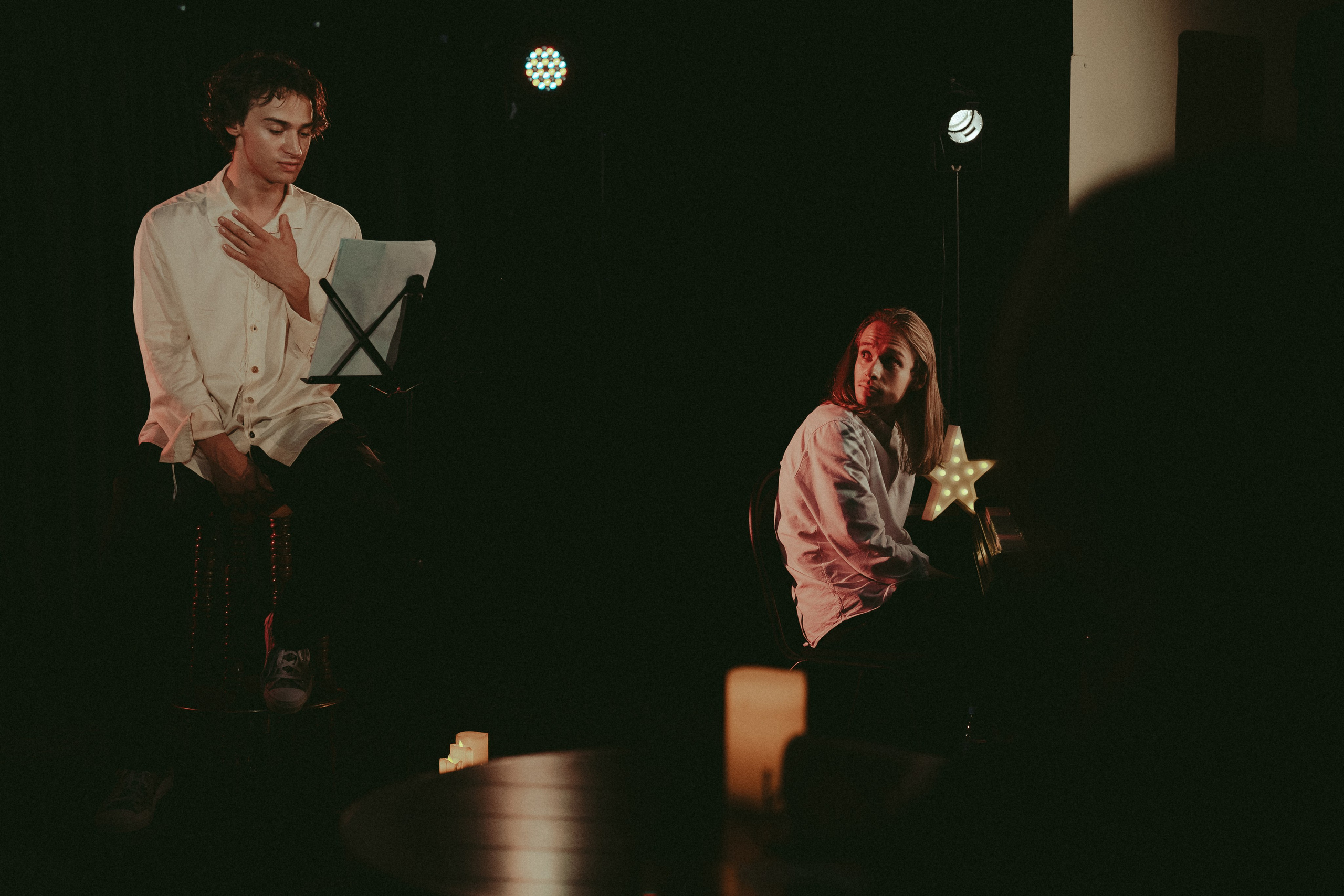 Двое артистов в белых рубашках на сцене: один читает текст с листа, другой сидит рядом и смотрит в сторону. Вечер Мандельштама, Актёр Андрей Мартынов. 