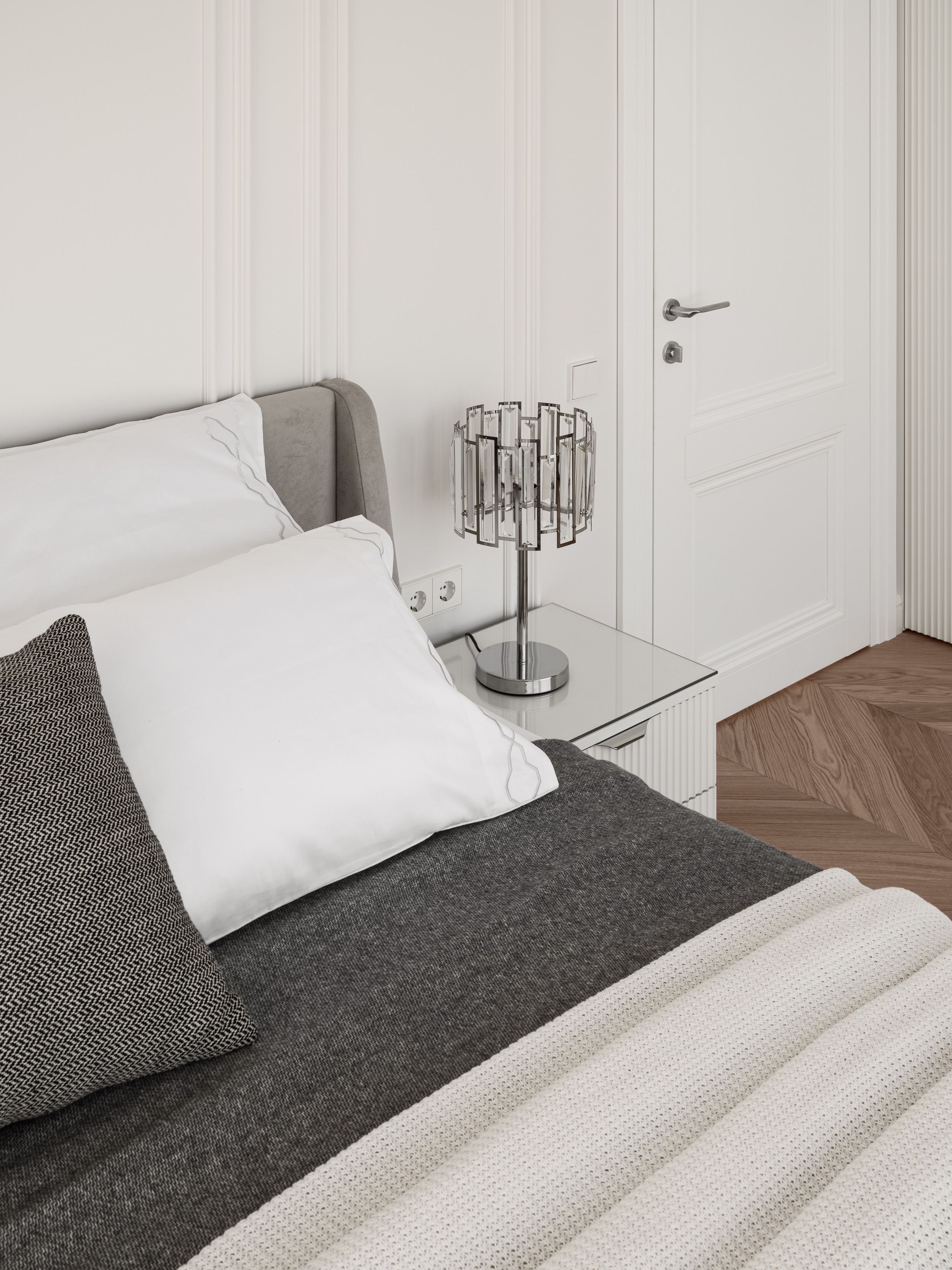 Минималистичная композиция у кровати с серым изголовьем, белыми подушками и зеркальной тумбой в интерьере спальни от Алёны Боярской. Наталья Якушева создала чистый визуальный ритм, а фотограф Сергей Денисенко акцентировал игру света на деталях современного дизайна.