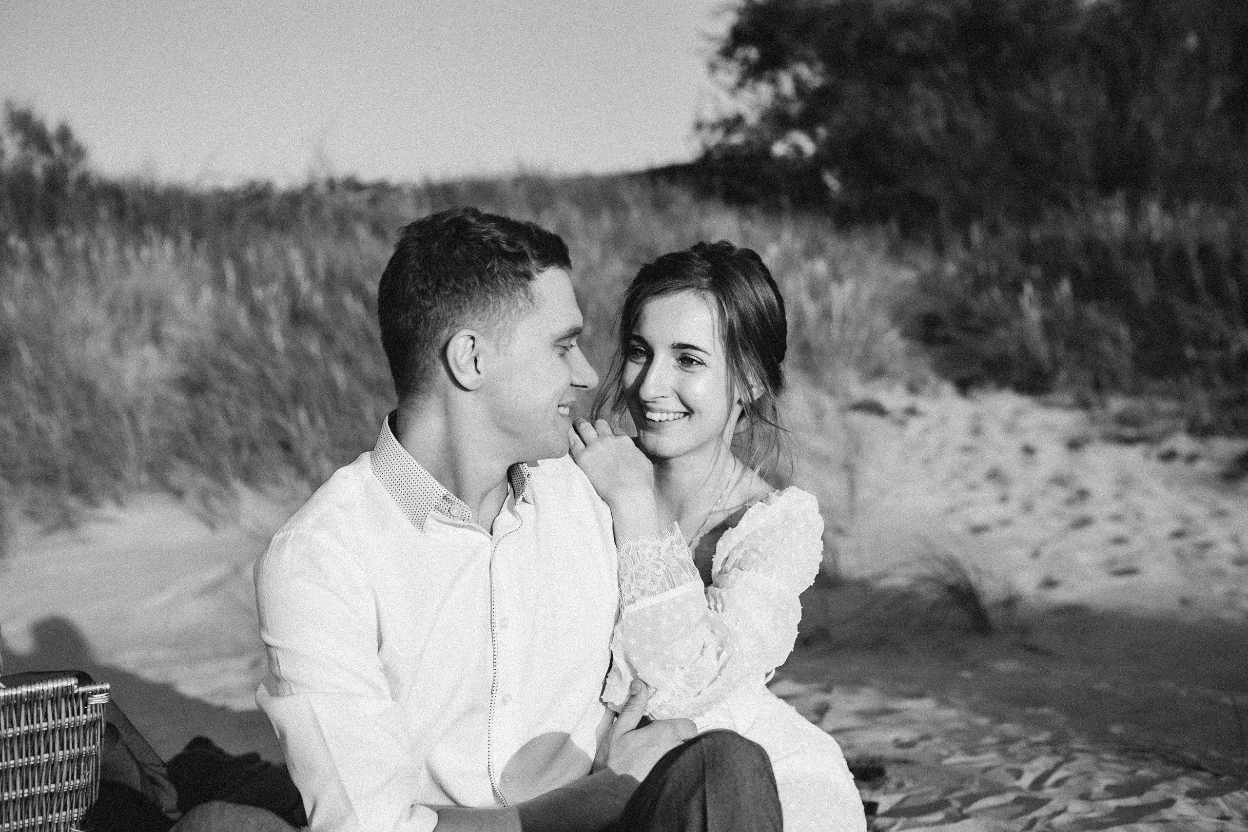 Love story на море: пара держится за руки на песке, босиком, волны накатывают на ноги. Романтика и нежность в каждом кадре.