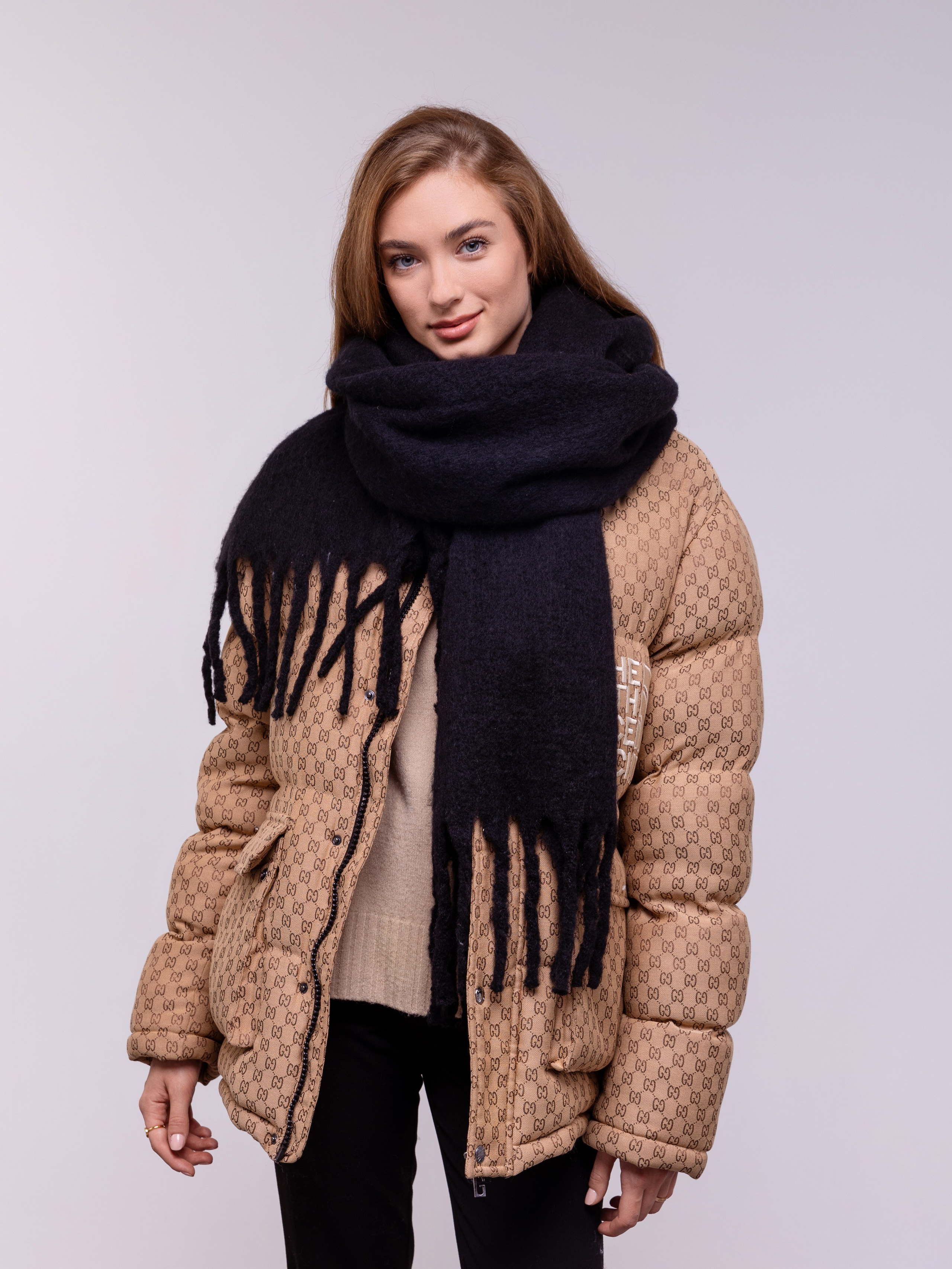 Черный шарф с большой бахромой гармонирует с коричневой курткой девушки.