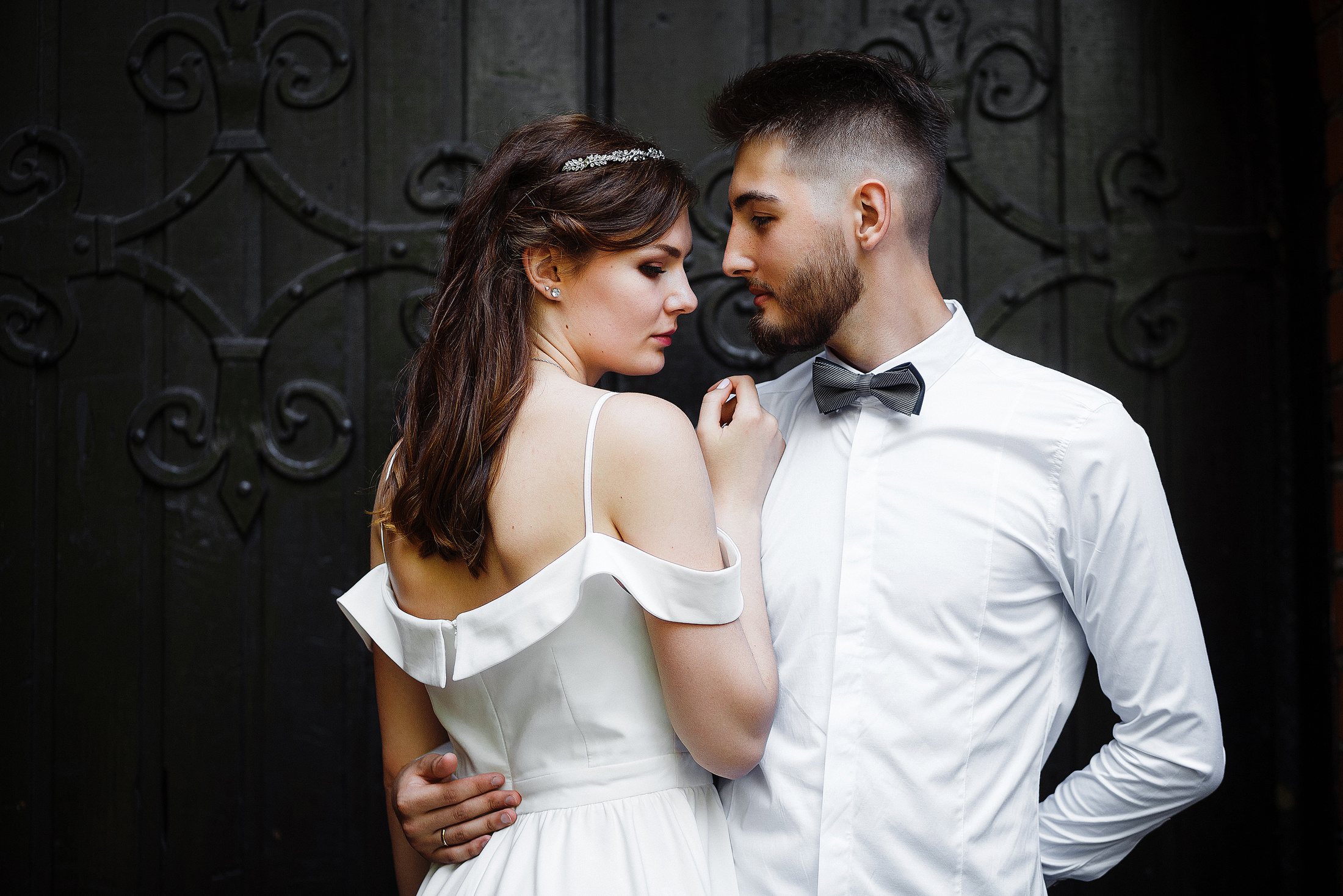 Стильная свадьба: жених и невеста в белом обнимаются у входа в Кафедральный собор