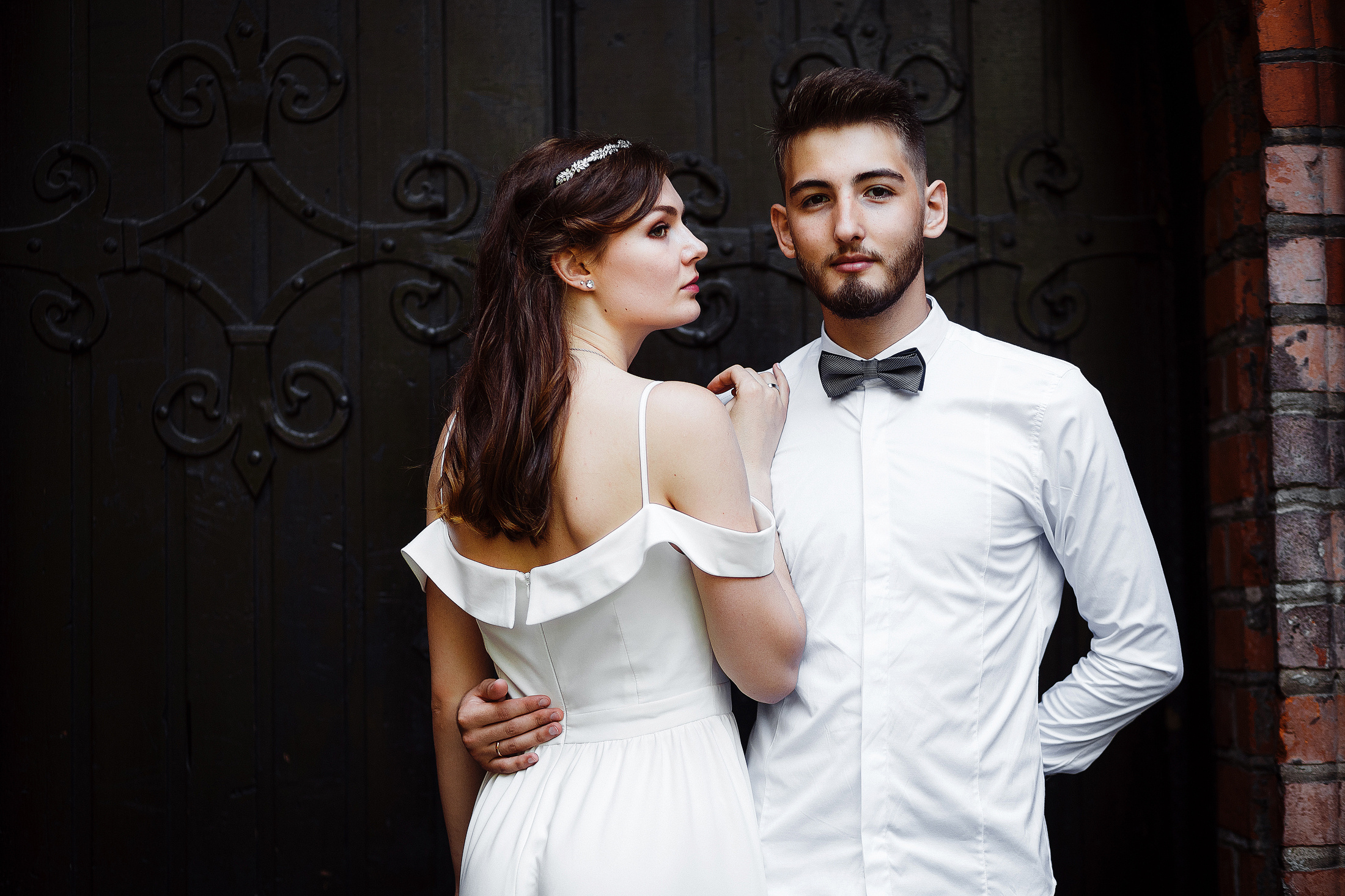 Стильное фото невесты и жениха на фоне темных старинных ворот