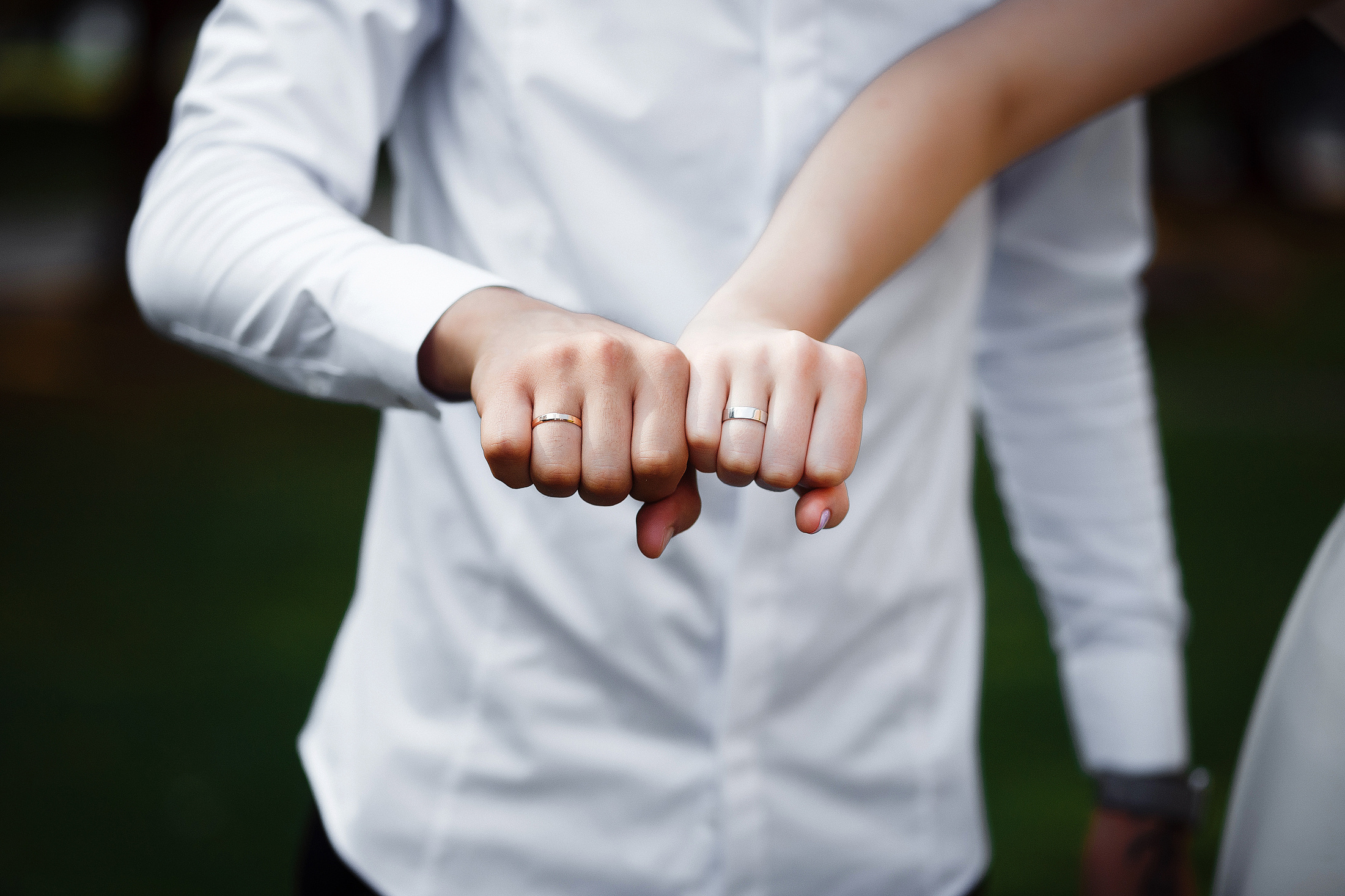 Молодожены демонстрируют обручальные кольца, сжав руки в кулаки