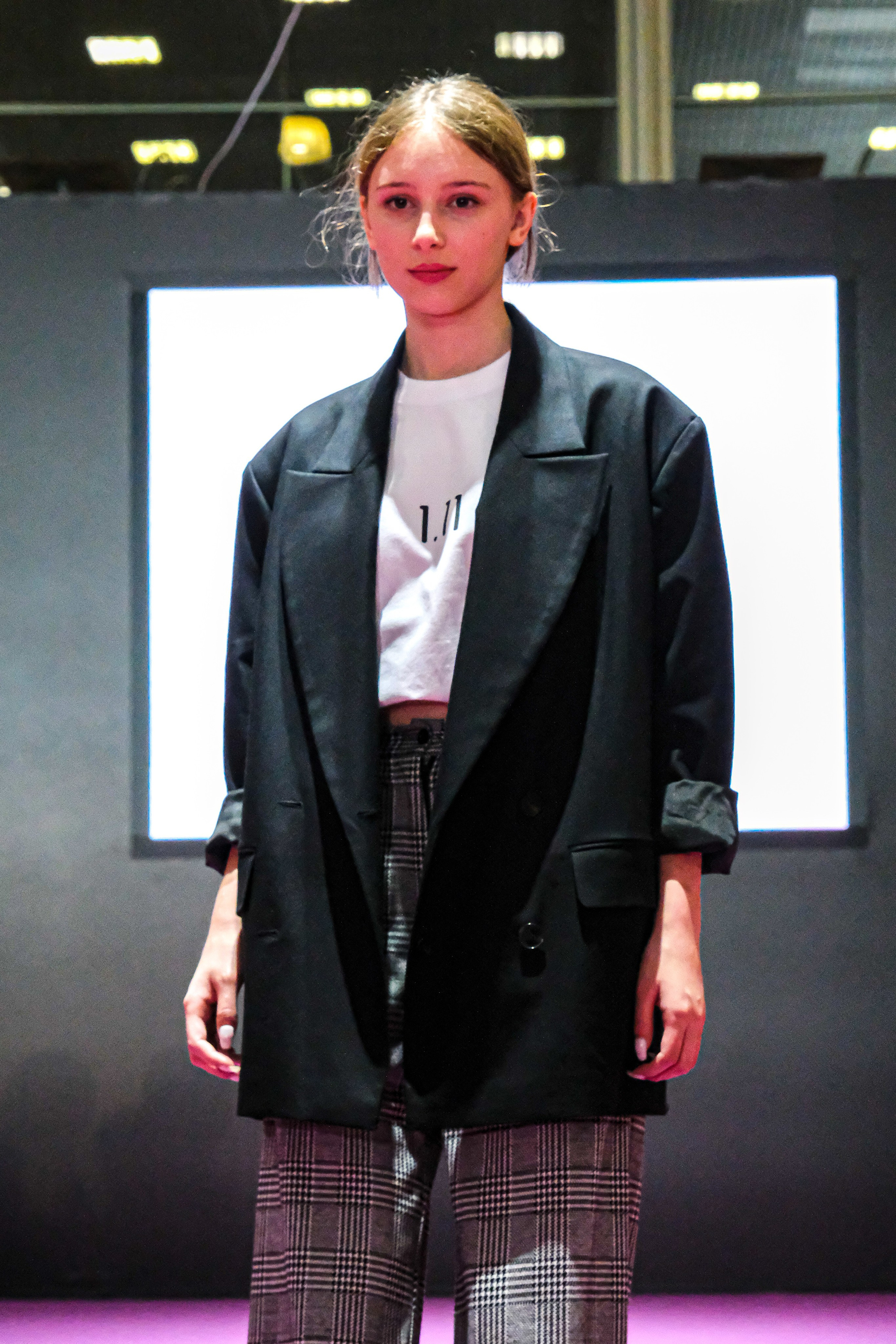  "Модели в ярких нарядах проходят по подиуму во время показа мод, освещенные яркими софитами и окруженные восторженными зрителями."