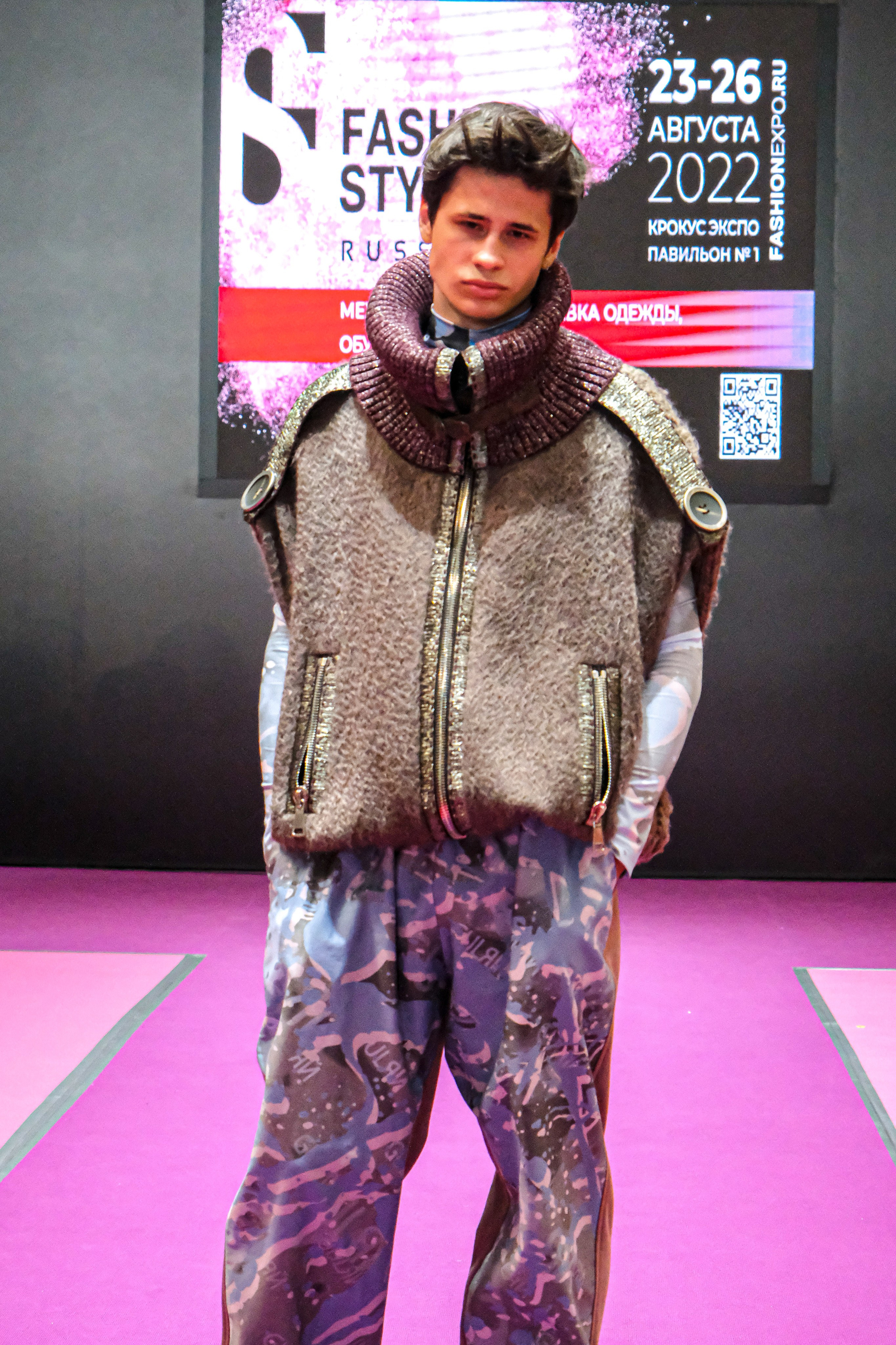  "Модели в ярких нарядах проходят по подиуму во время показа мод, освещенные яркими софитами и окруженные восторженными зрителями."