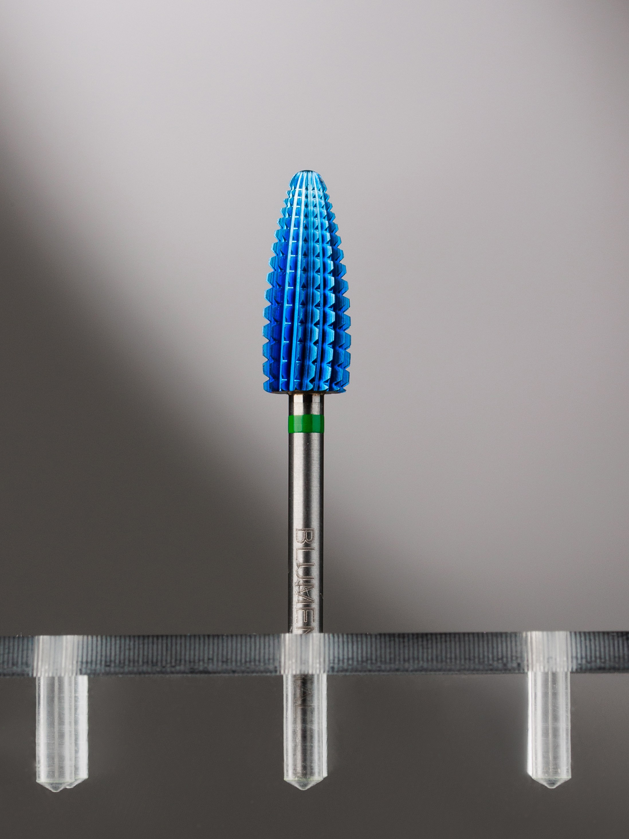 имиджевая предметная съемка фреза для маникюра на прозрачной подставке на сером подсвеченном фоне