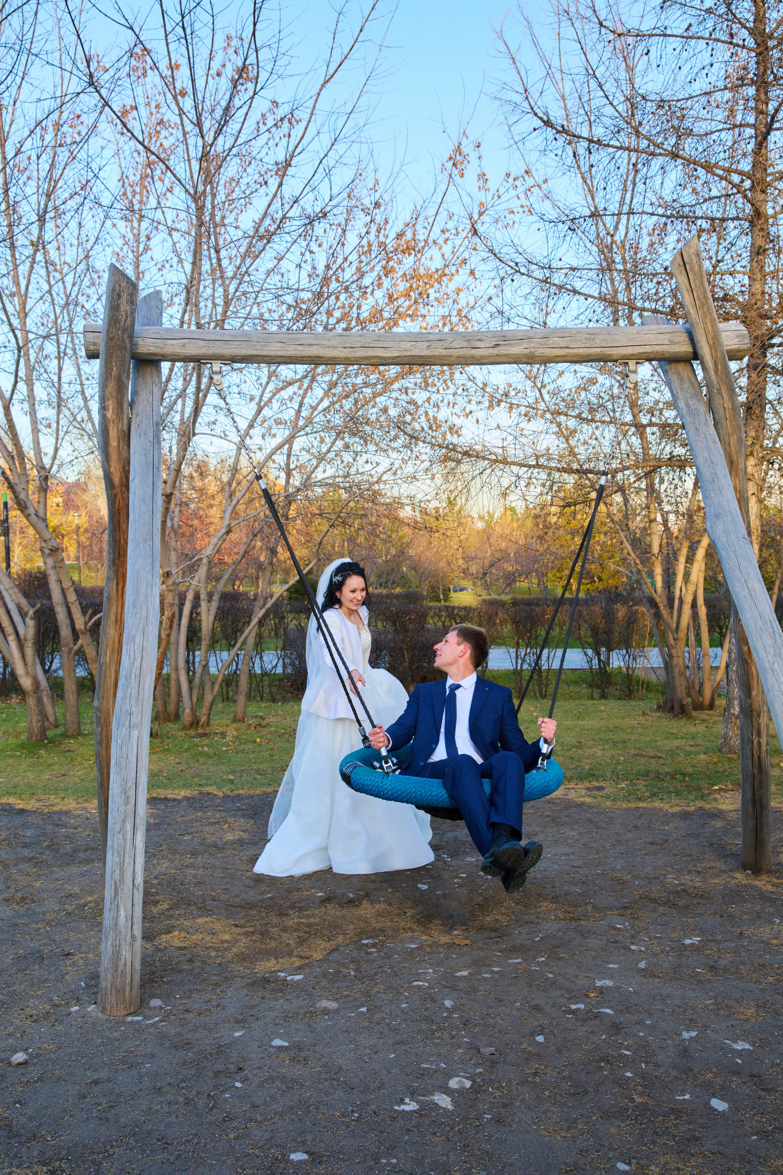 Жениха качает невеста на качелях