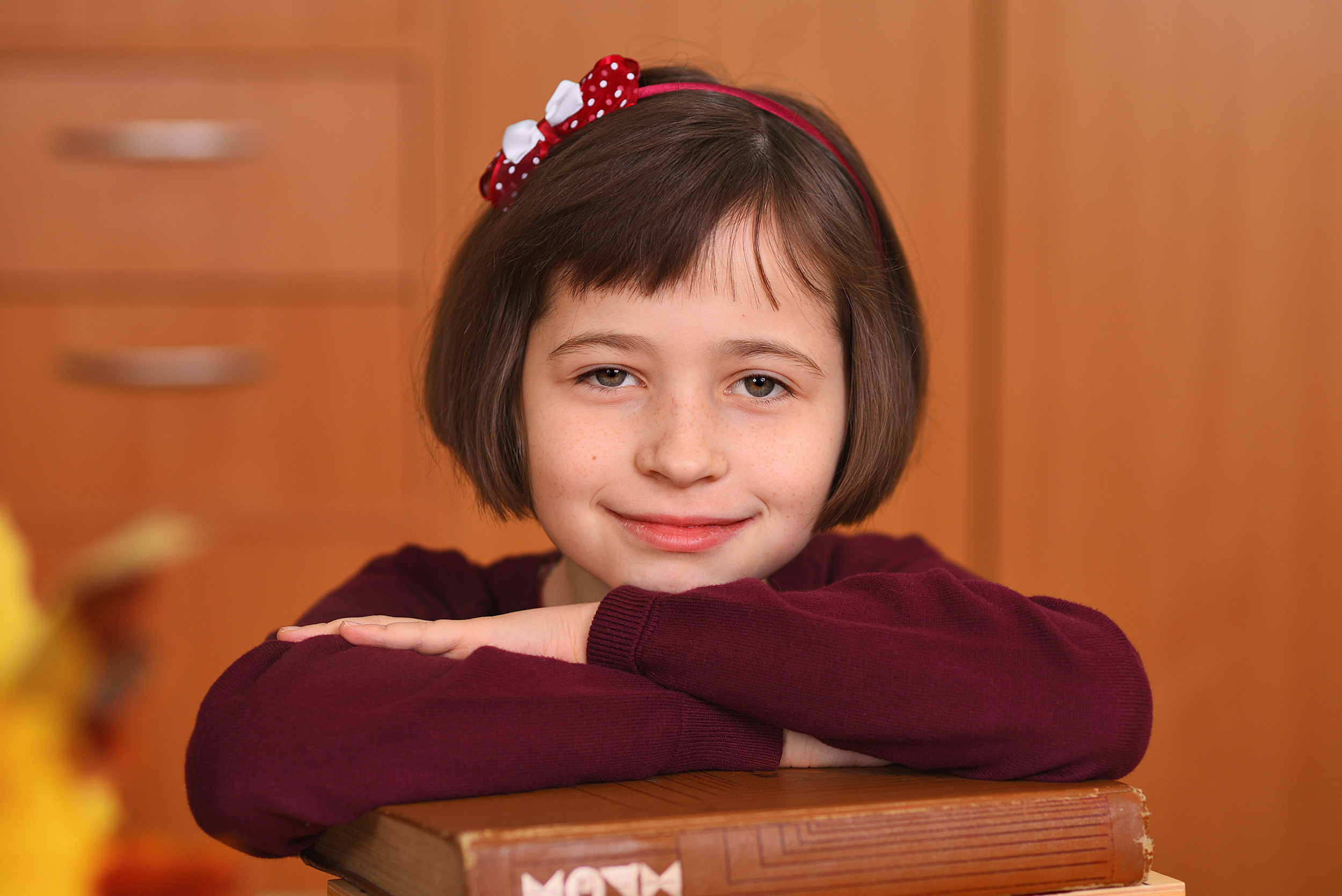 Крупный портрет школьницы, положившей руки и подбородок на книги.