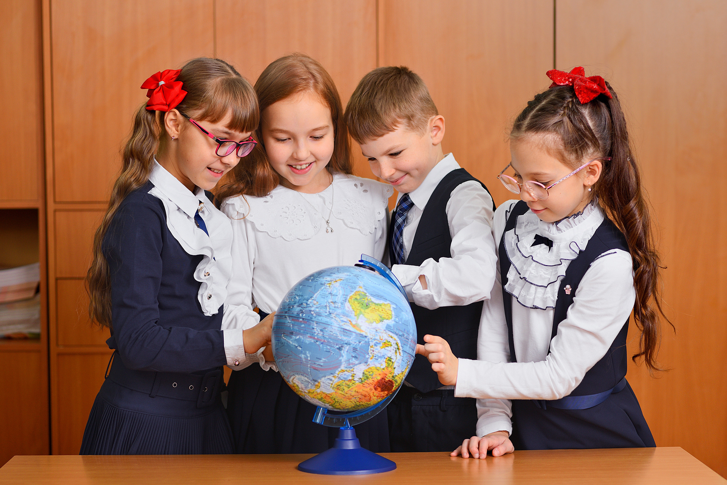 Портрет школьников в классе, разглядывающих глобус.