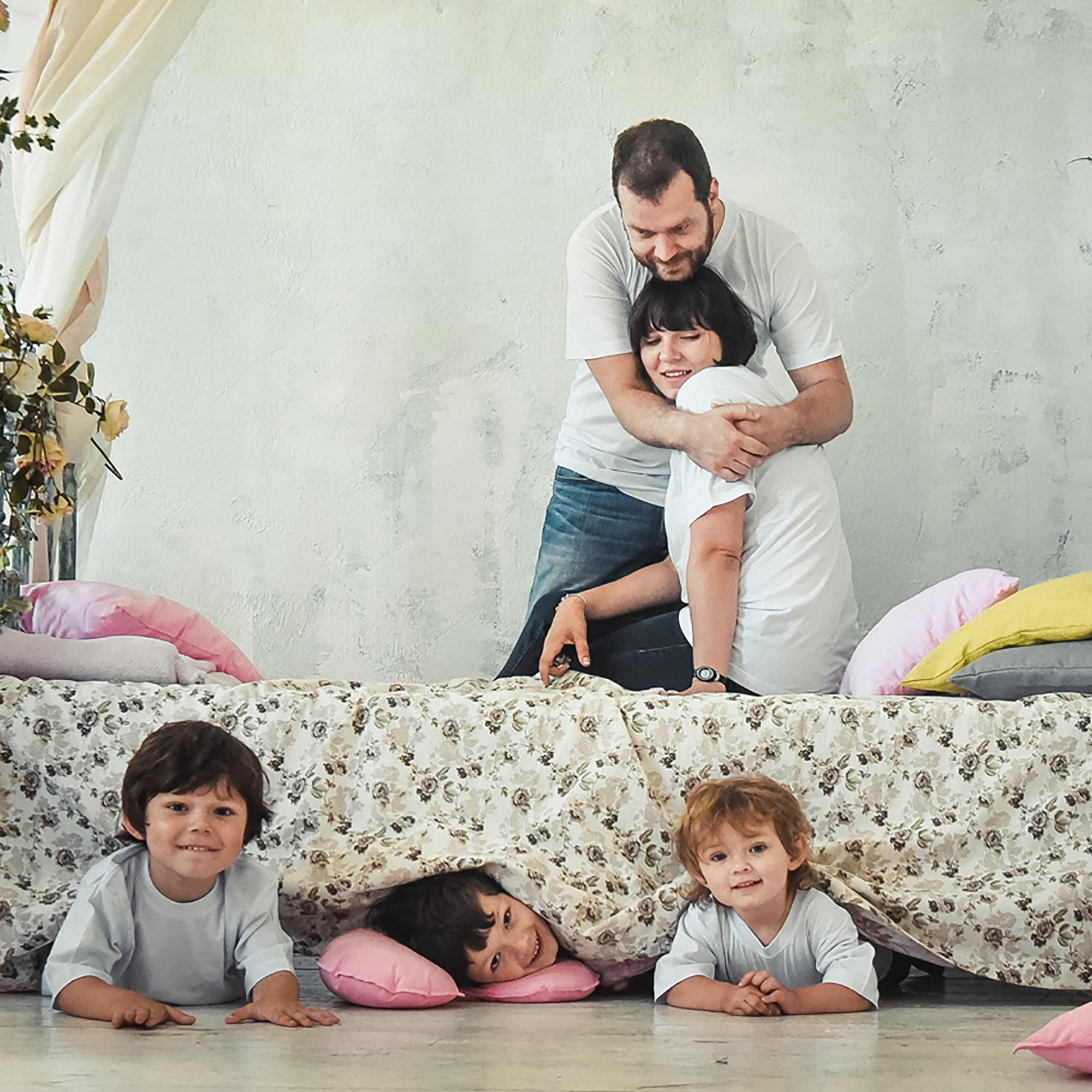 Мама и папа, обнимающие друг друга, а дети весело играют рядом