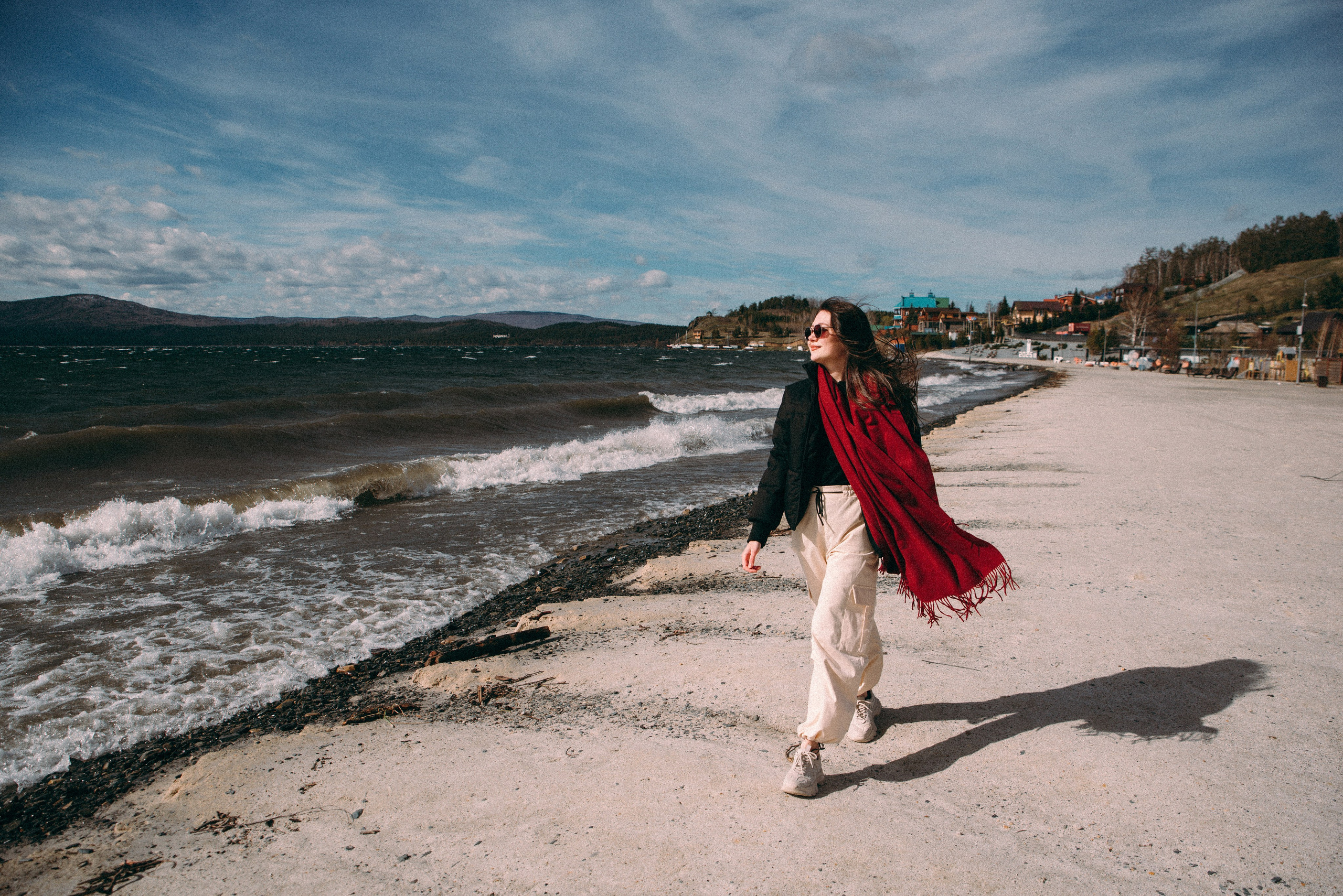 девушка в красном шарфе идет по берегу озера