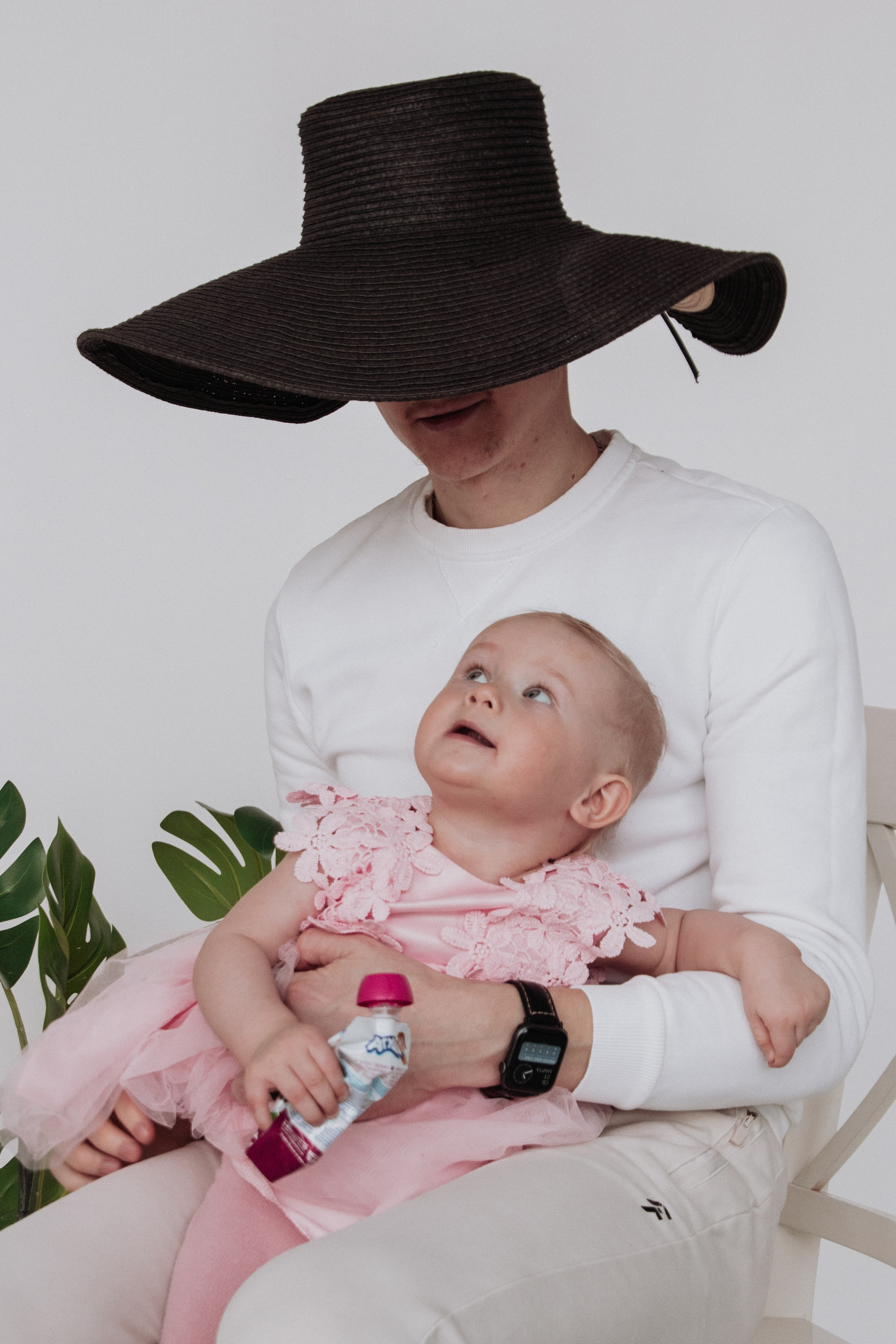 папа сидит в шляпе на голове и держит на руках свою маленькую любопытную дочку