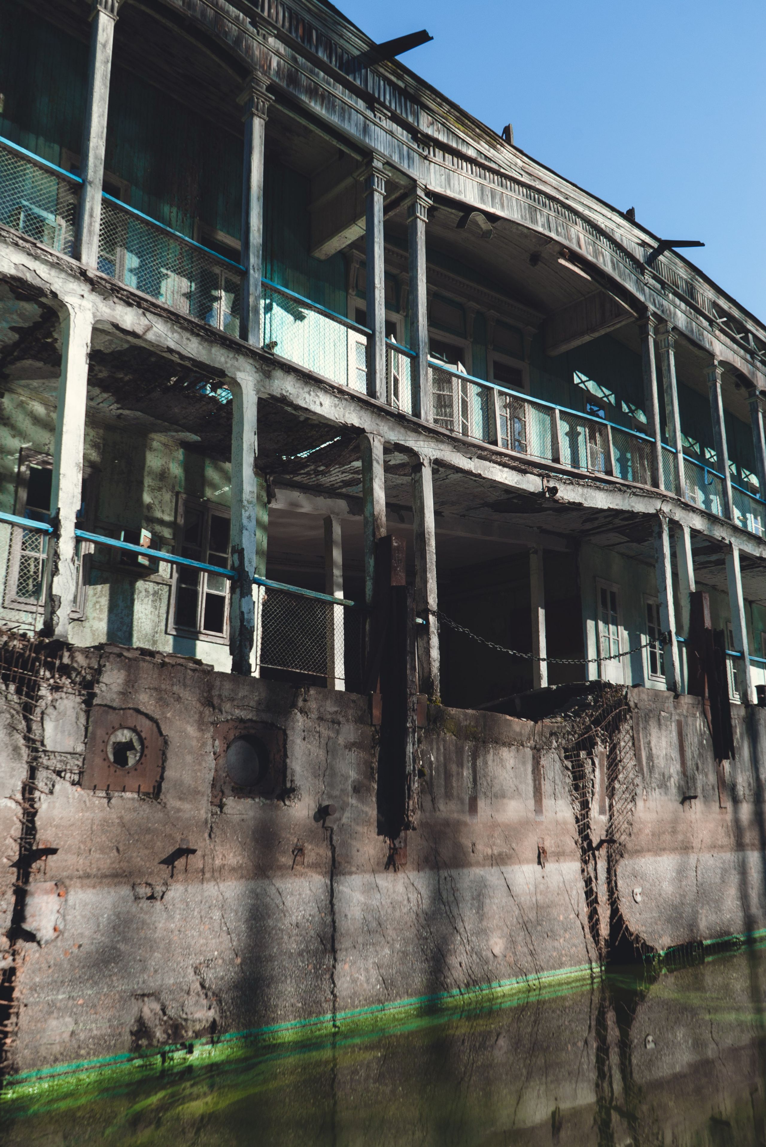 Заброшенное здание, виднеющееся на старинном берегу речной пароход, стоит на водоеме среди густого леса. Его фасад украшен колоннами и балконами, однако здание выглядит ветхим и запущенным: краска облупилась, металл покрыт ржавчиной. Вокруг голые деревья и хвойные леса, что создает ощущение уединенности и застенчивости.