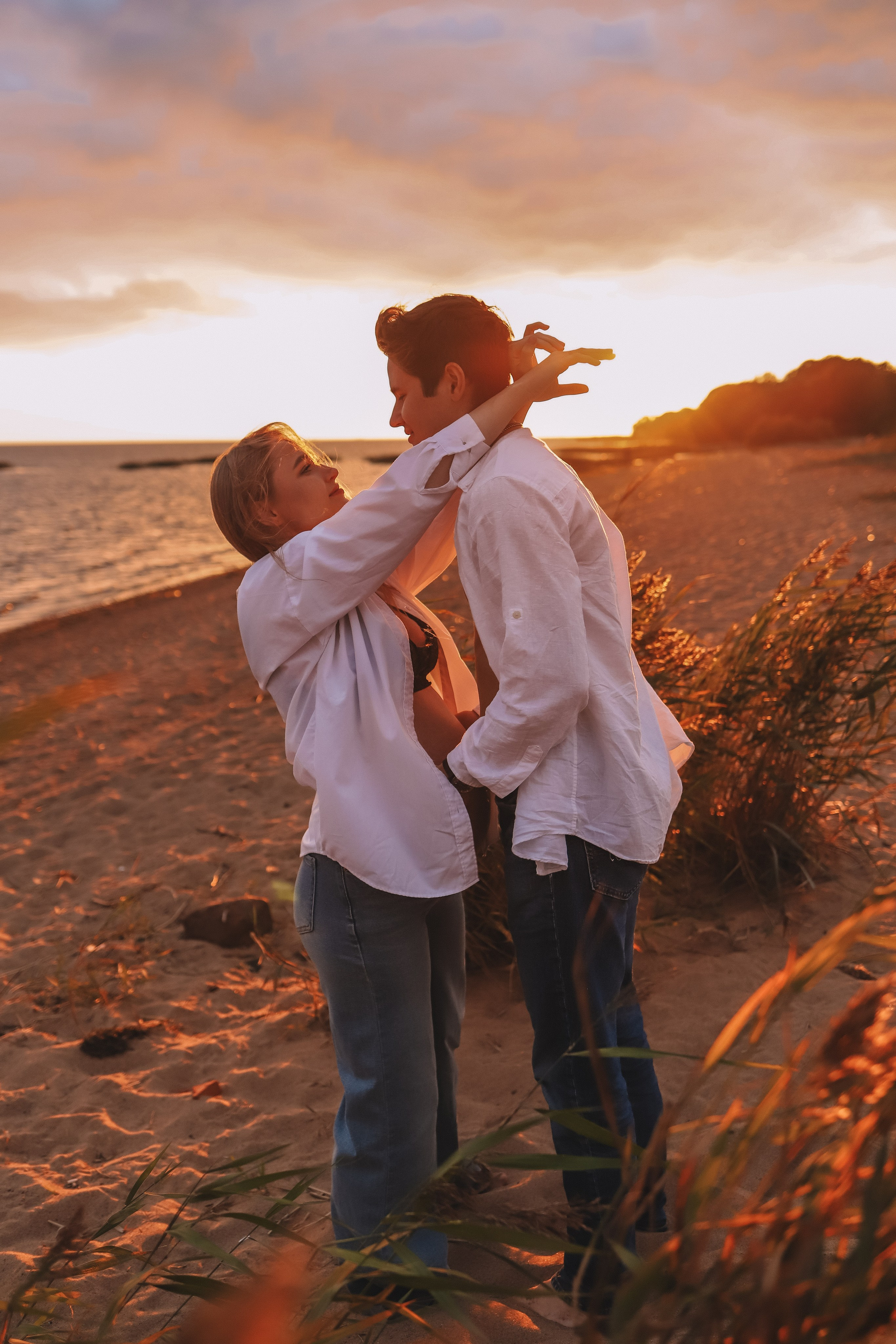 Мужчина поднимает девушку на руки, закат