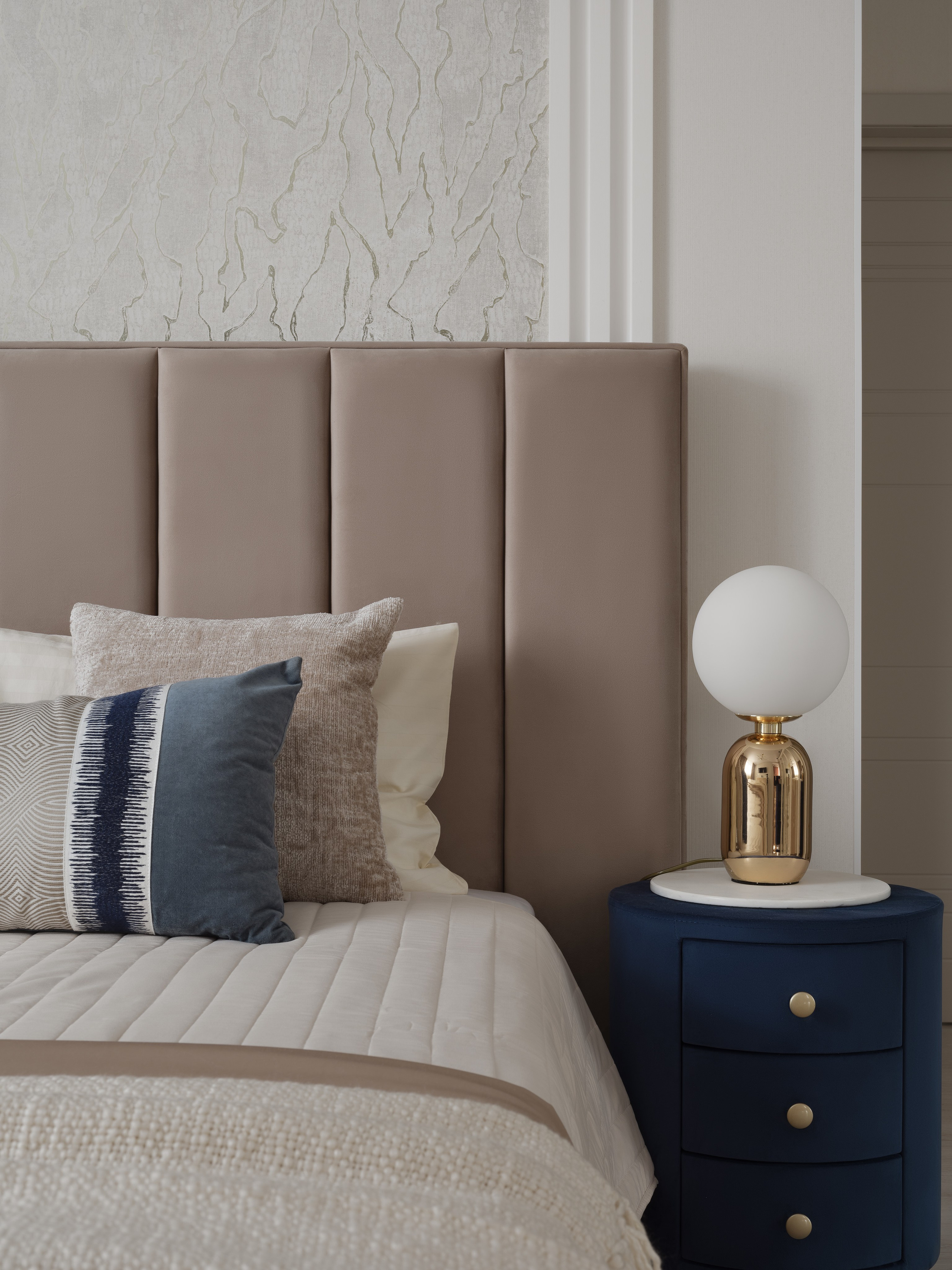 Интерьер спальни в современном стиле с мягким изголовьем кровати, стильной прикроватной тумбой и акцентами в золотых тонах, уют и элегантность, фото дизайнера Ольги Рубченко, стилиста Екатерины Ракитиной и фотографа Сергея Денисенко.