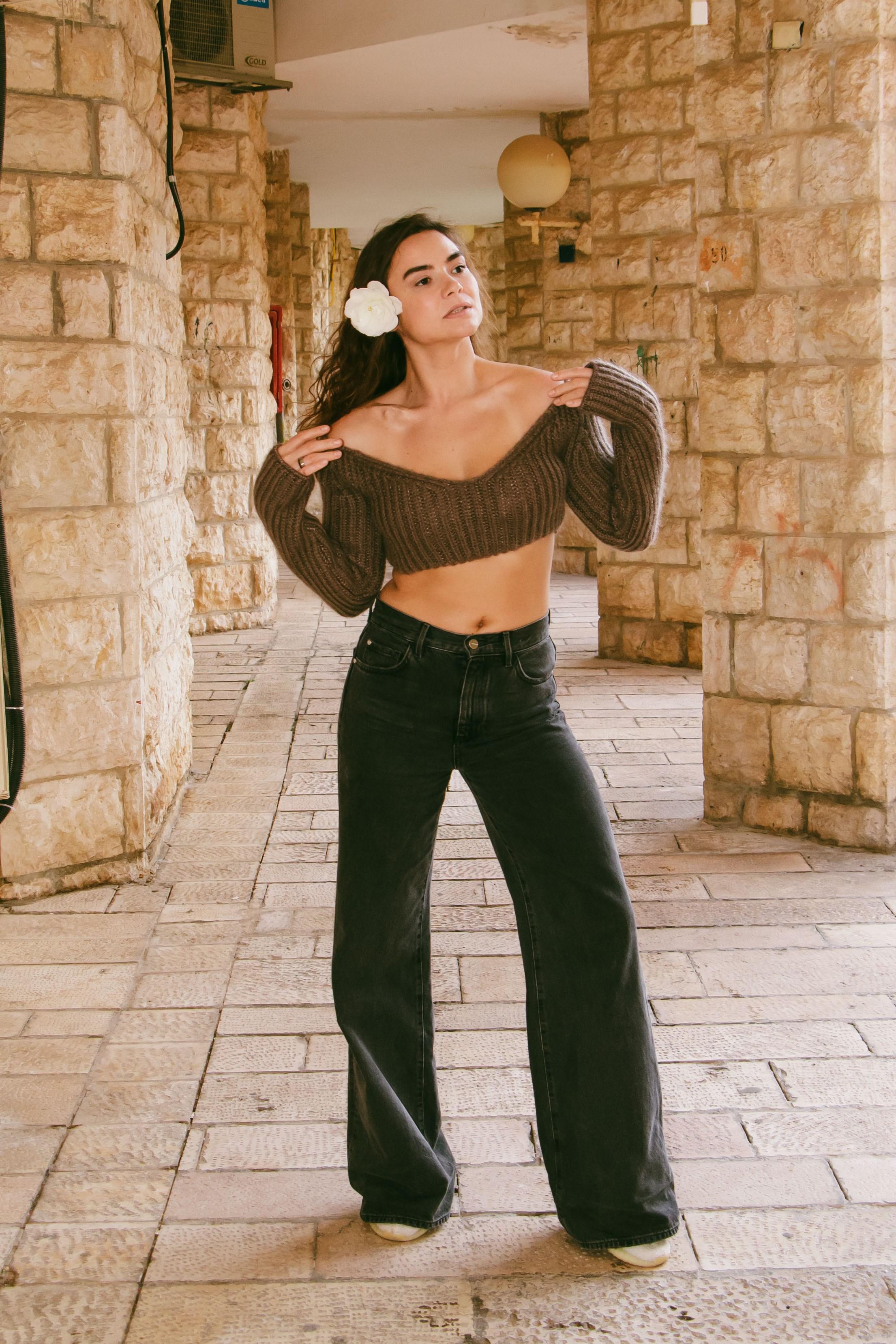 стройная девушка в полный рост стоит возле каменного дома 