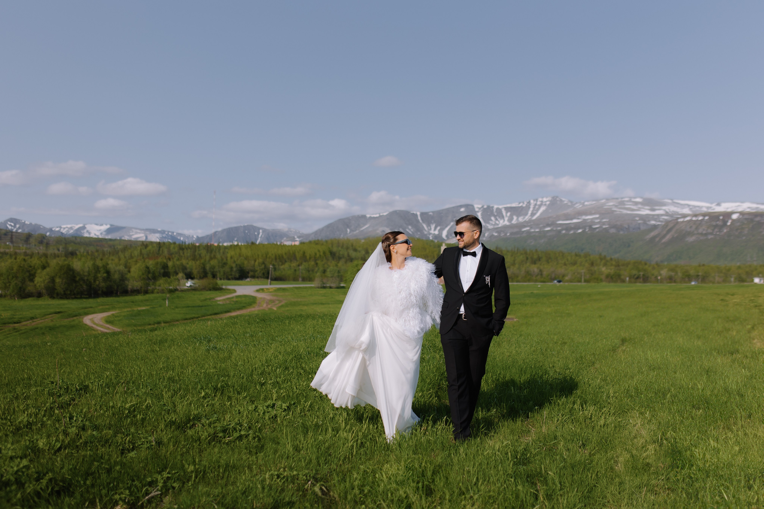 Поцелуй молодых супругов на смотровой площадке в солнечный летний день.