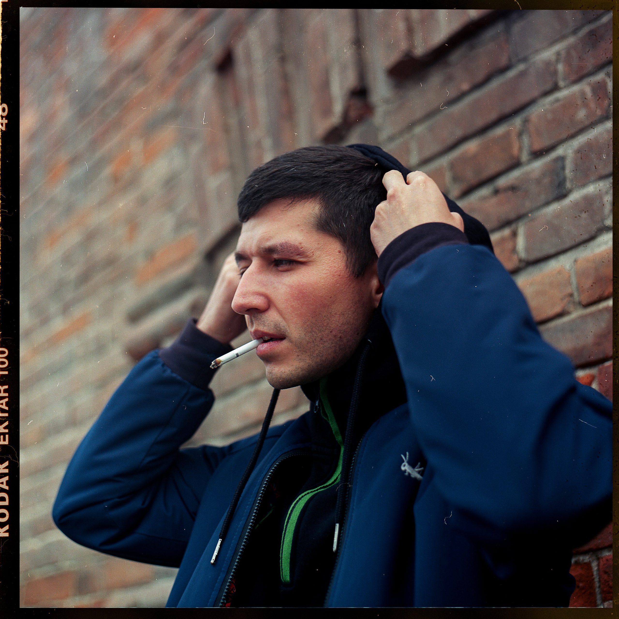 Парень с сигаретой во рту надевает капюшон