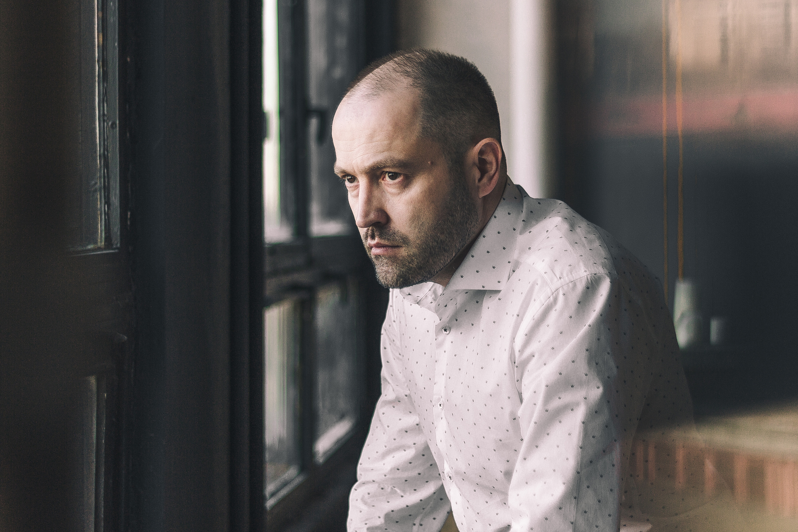 Мужчина в рубашке стоит у окна