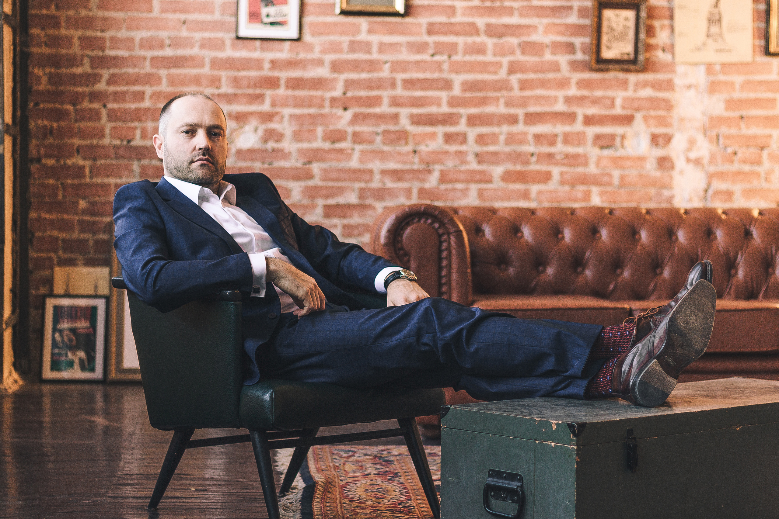 Мужчина в синем деловом костюме сидит в кресле