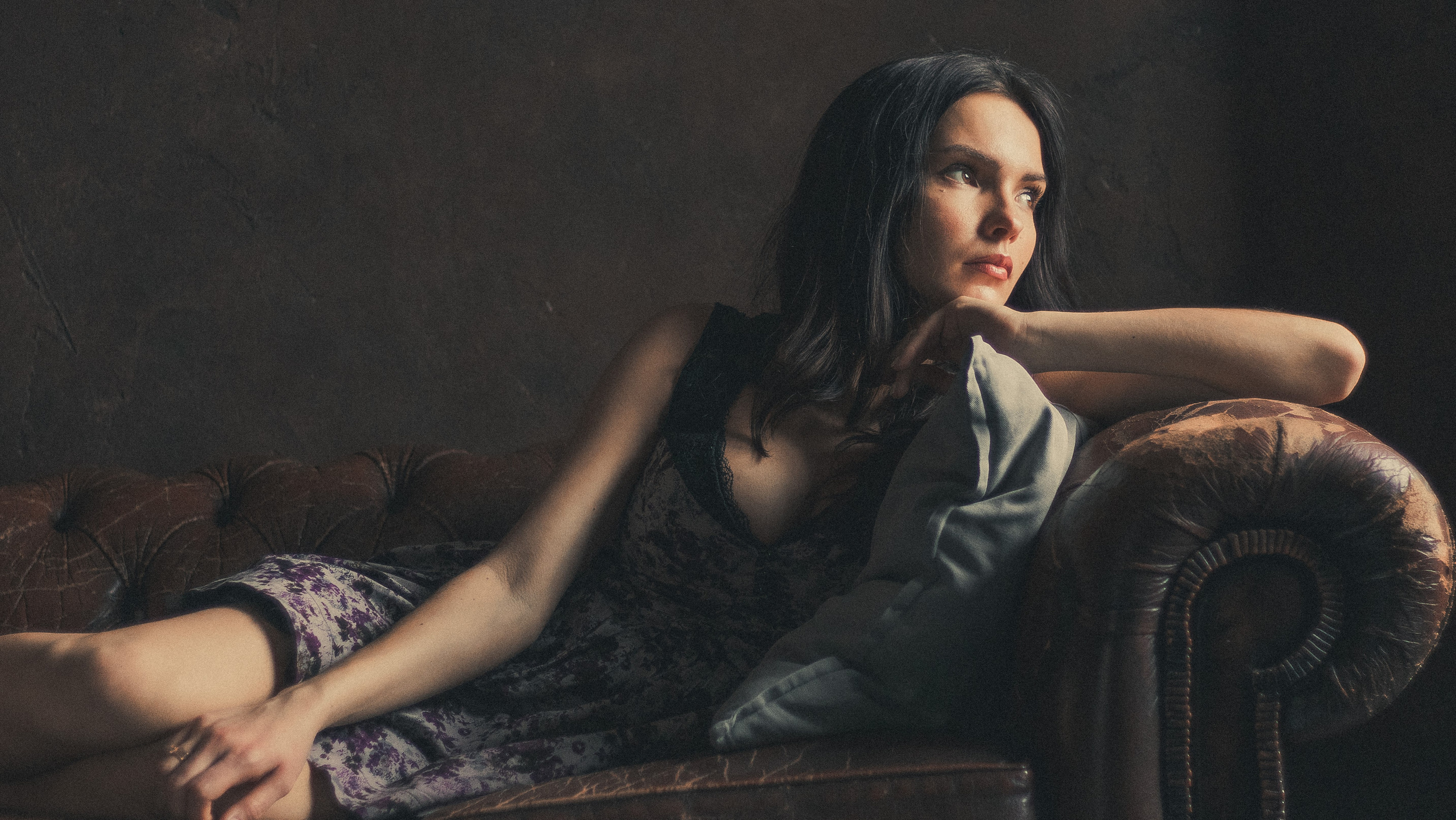 Девушка в платье с декольте лежит на диване и смотрит в окно. Фотограф Андрей Соболев.