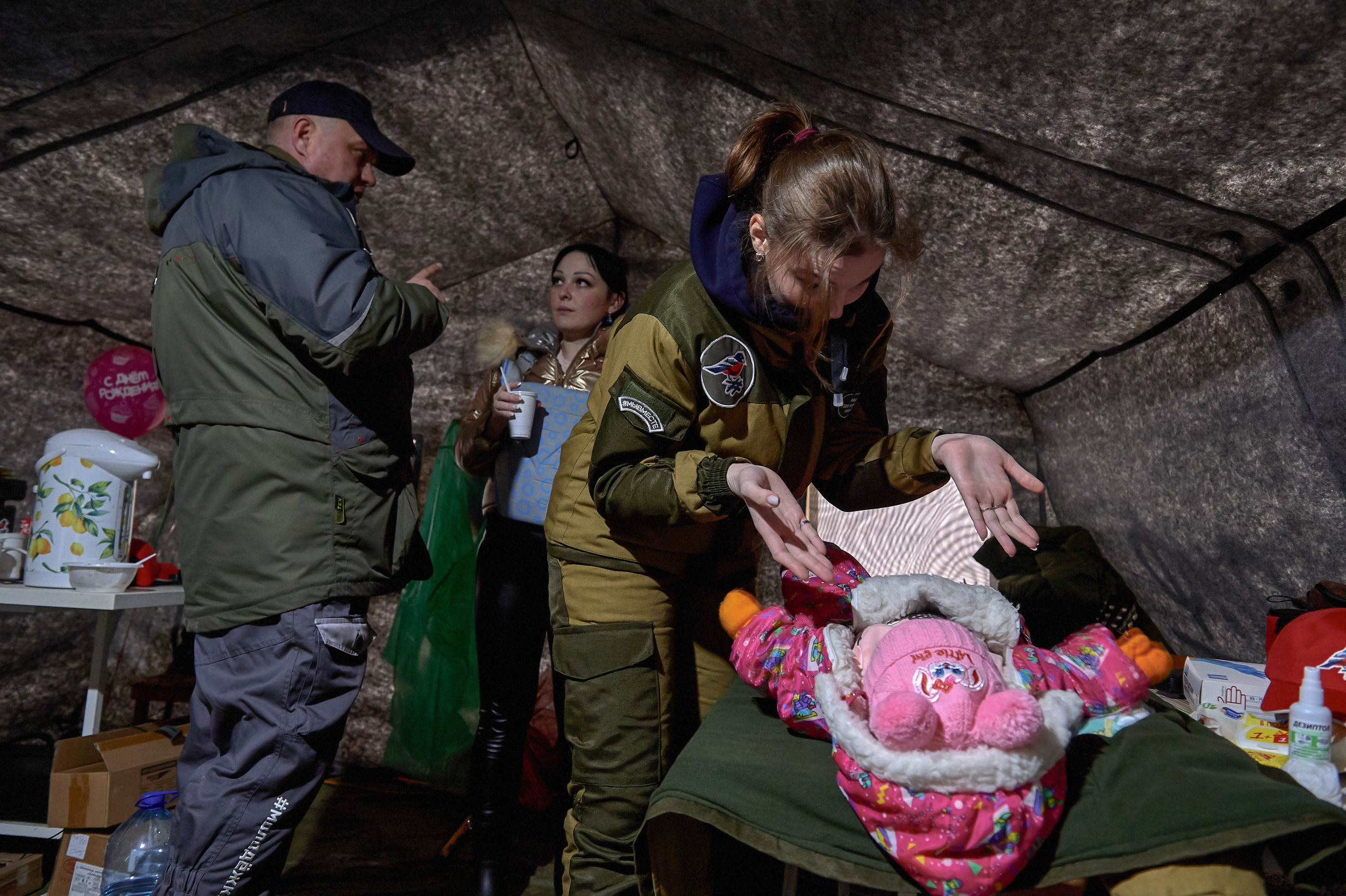 A volunteer doctor examines a child while their mother, from Donetsk, speaks with Russian Senator Igor Kastyukevich in a tent near the border checkpoint in Avilo-Uspenka village, Rostov region, on the day of Russia's full-scale invasion of Ukraine, February 24, 2022.