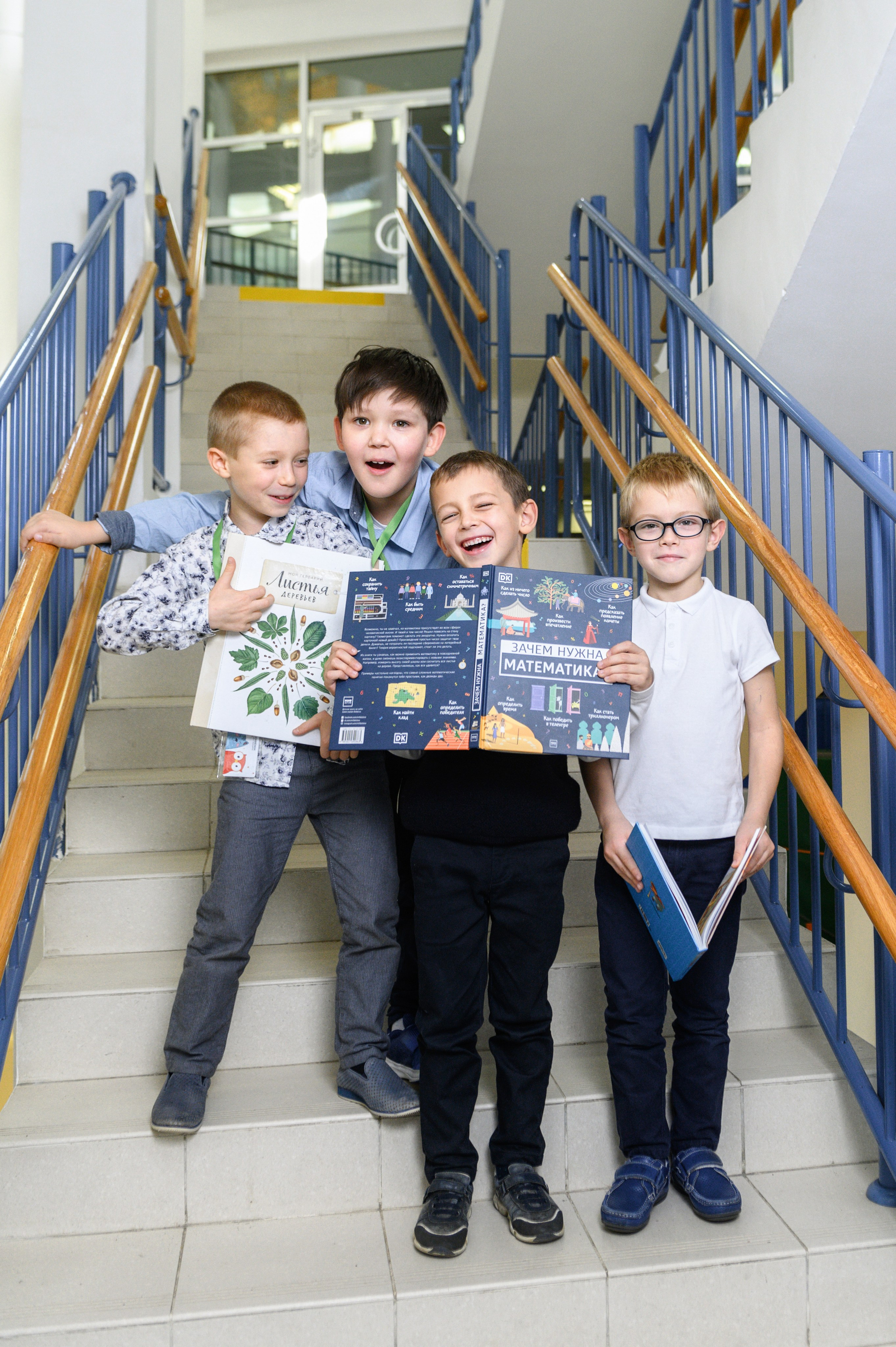 Четверо школьников стоят на лестнице с книгой в руках