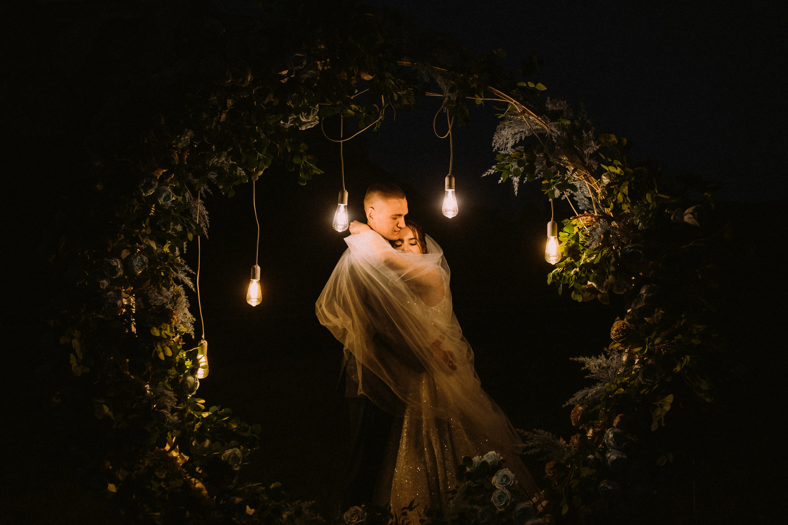 влюбленные под с лампочками аркой ночью